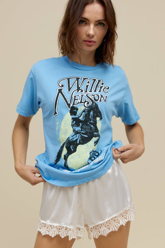 A model featuring a blue weekend tee stamped with Willie Nelson and his route 66 album cover.