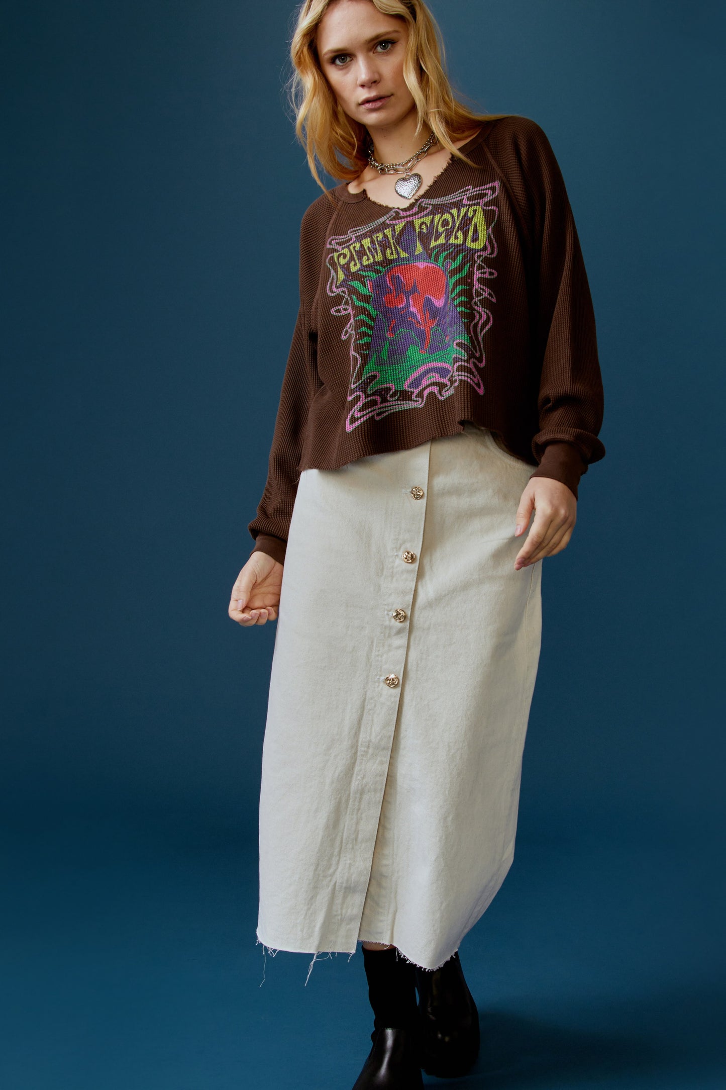 A blonde-haired model featuring a brown long sleeve stamped with 'Pink Floyd' in yellow font and a graphic of a cosmic pyramid.