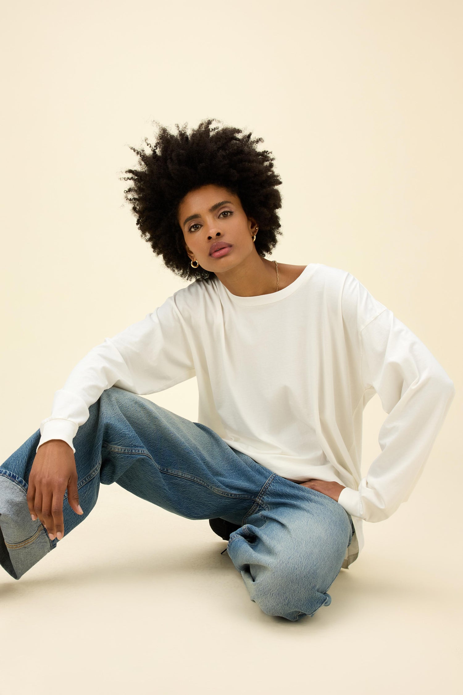 A model featuring a long sleeve merch in vintage white.