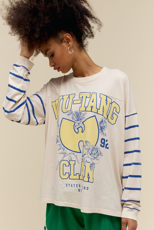 A model featuring a white varsity long sleeve stamped with Wu-tang Clan in large yellow font and their logo.