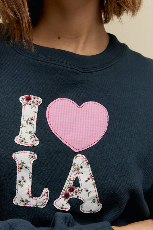 A model featuring a black crew sweatshirt stamped with I love LA.