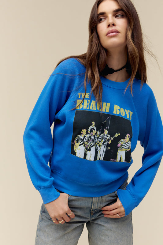 A model featuring a cobalt long sleeve designed with the band's group photo and stamped with the band's name.