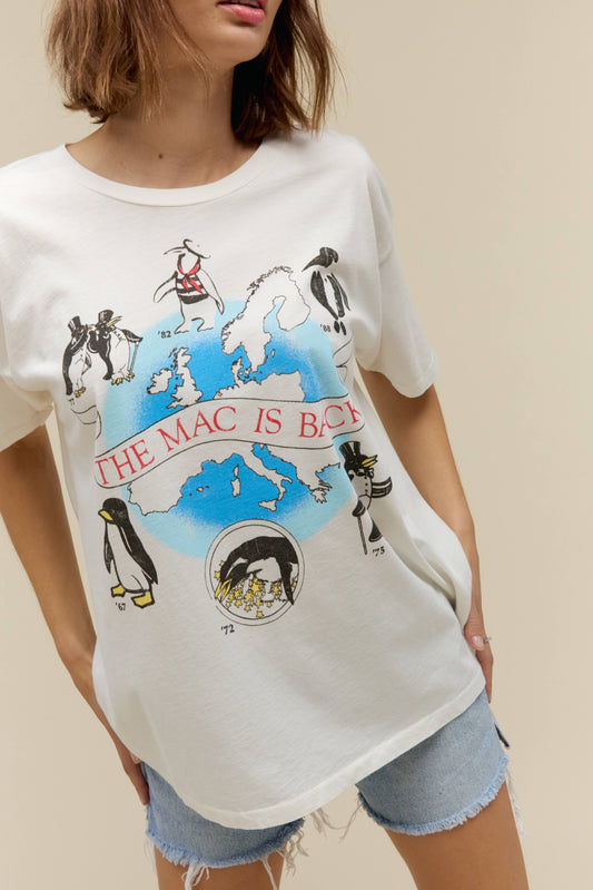 A model featuring a white merch tee stamped with 'The Mac Is Back' in red font with graphic penguins around.