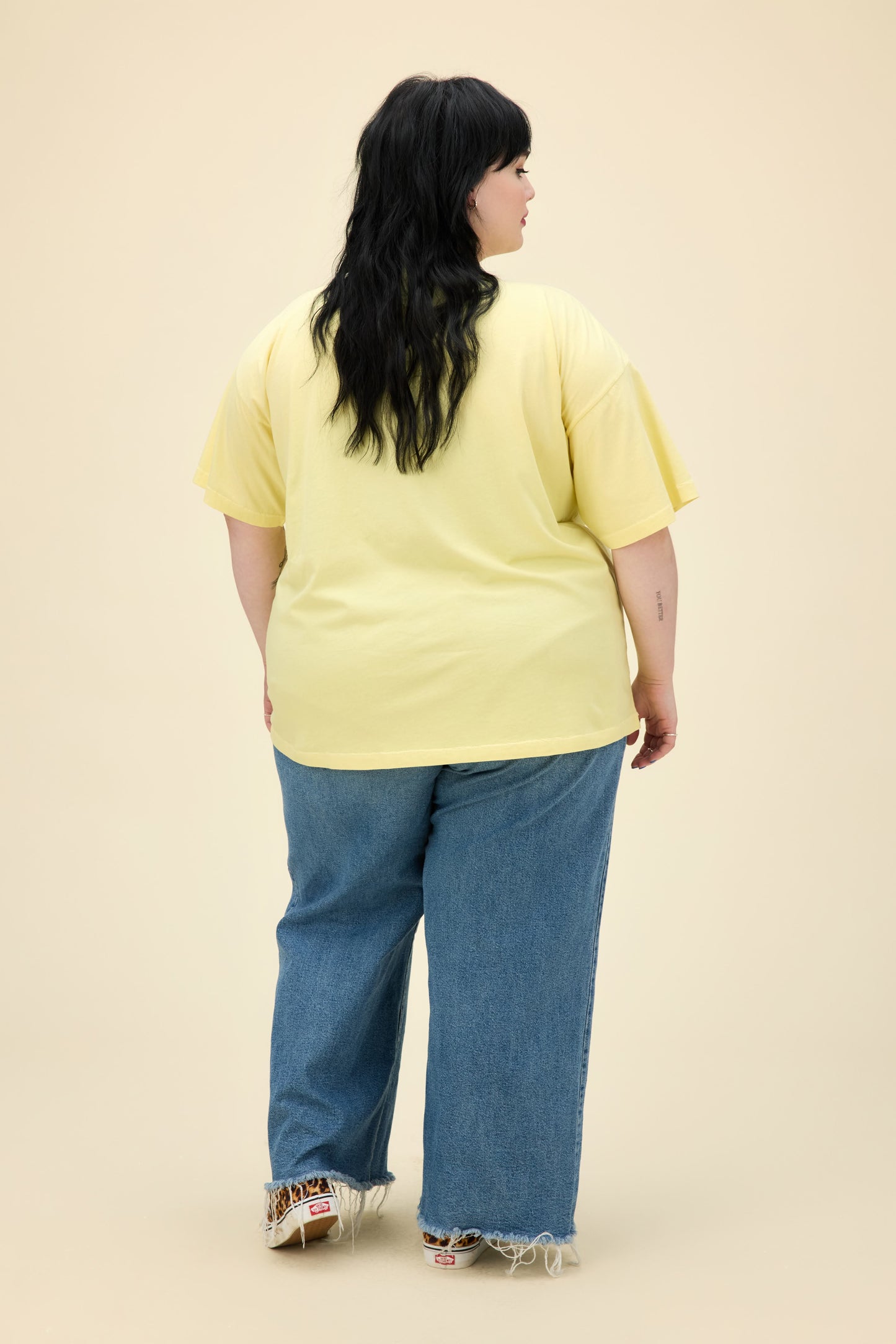 A model featuring a plus size yellow mist colored merch tee stamped with Nirvana's Utero album cover.