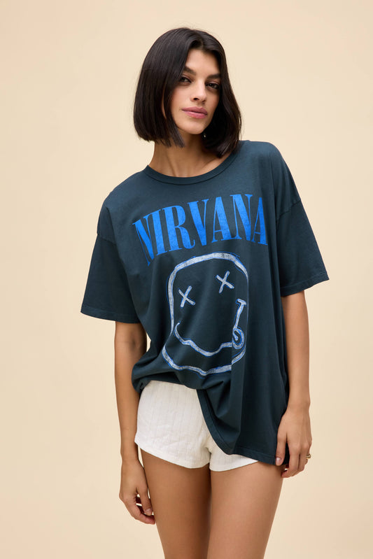 A model featuring a black smiley merch tee, stamped with "Nirvana" and the band's smiley logo.