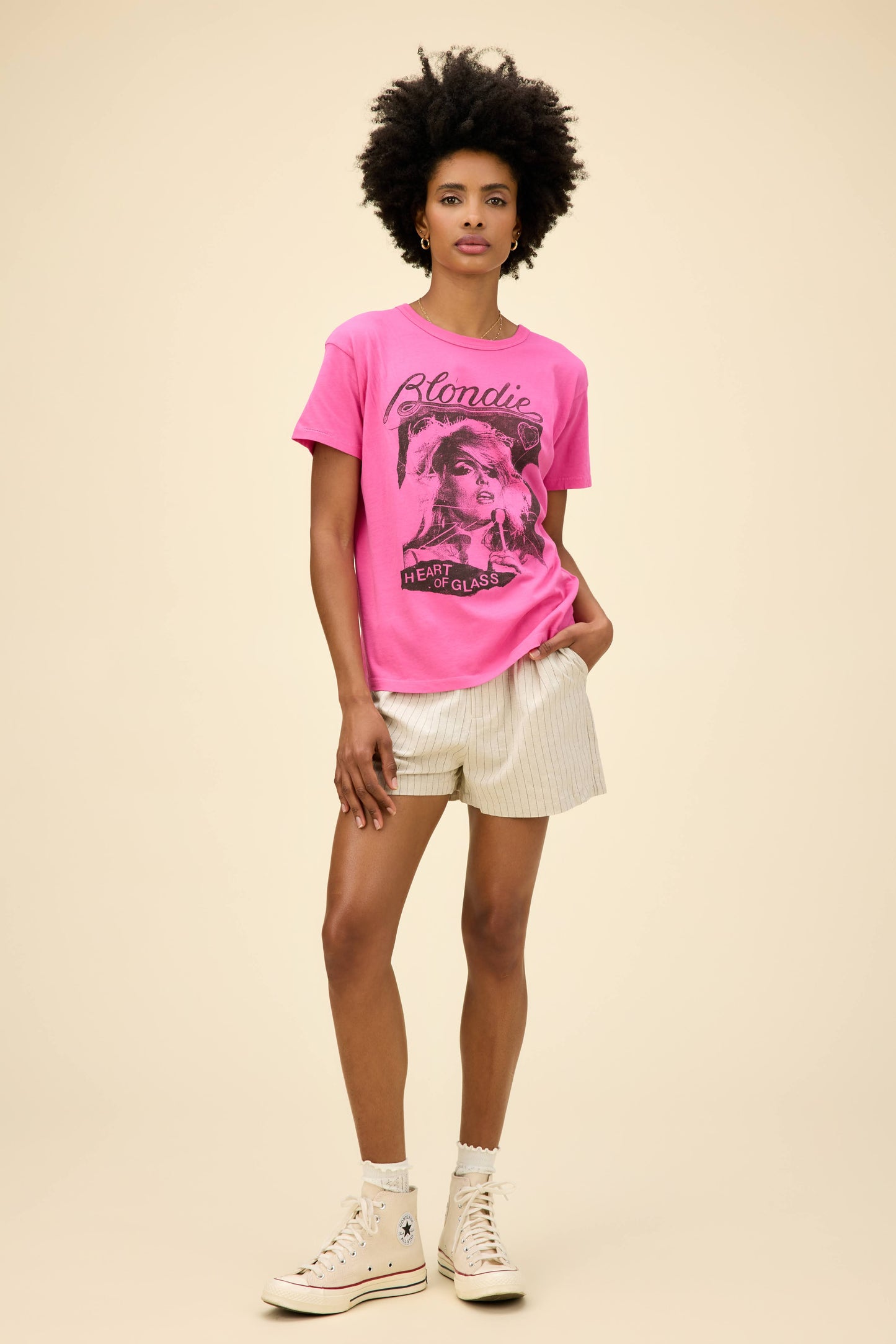 Curly-haired model wearing a Blondie graphic ringer tee in pink with 'Heart Of Glass' artwork on the front and back.