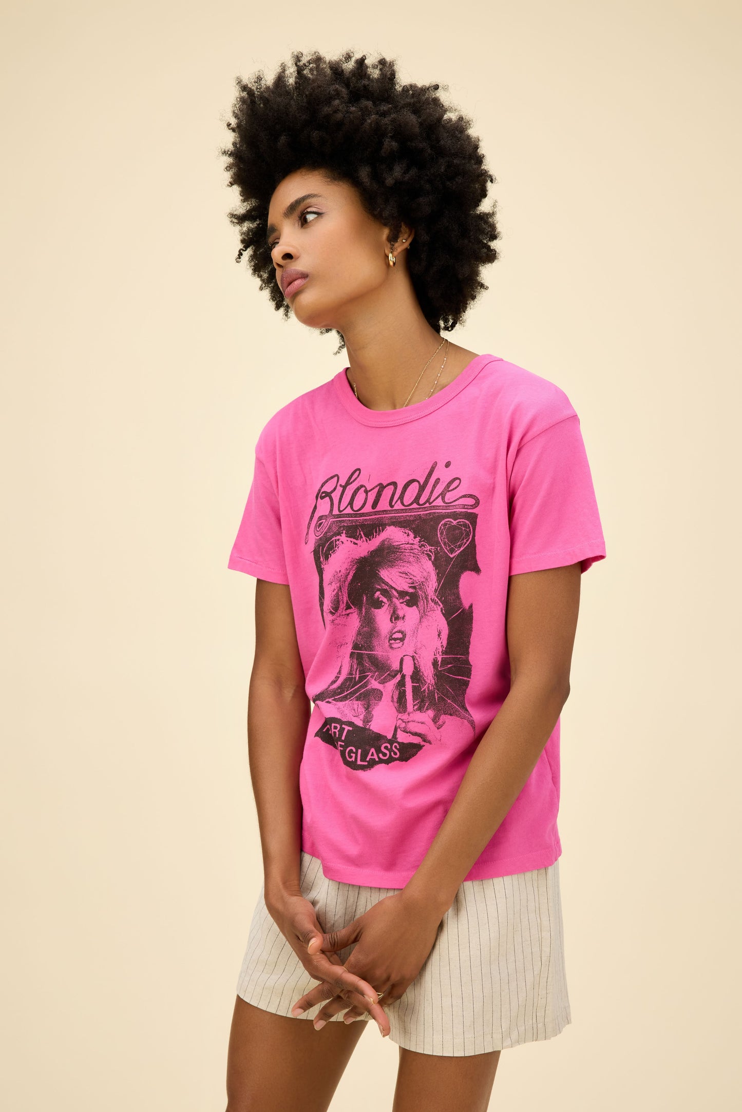 Curly-haired model wearing a Blondie graphic ringer tee in pink with 'Heart Of Glass' artwork on the front and back.