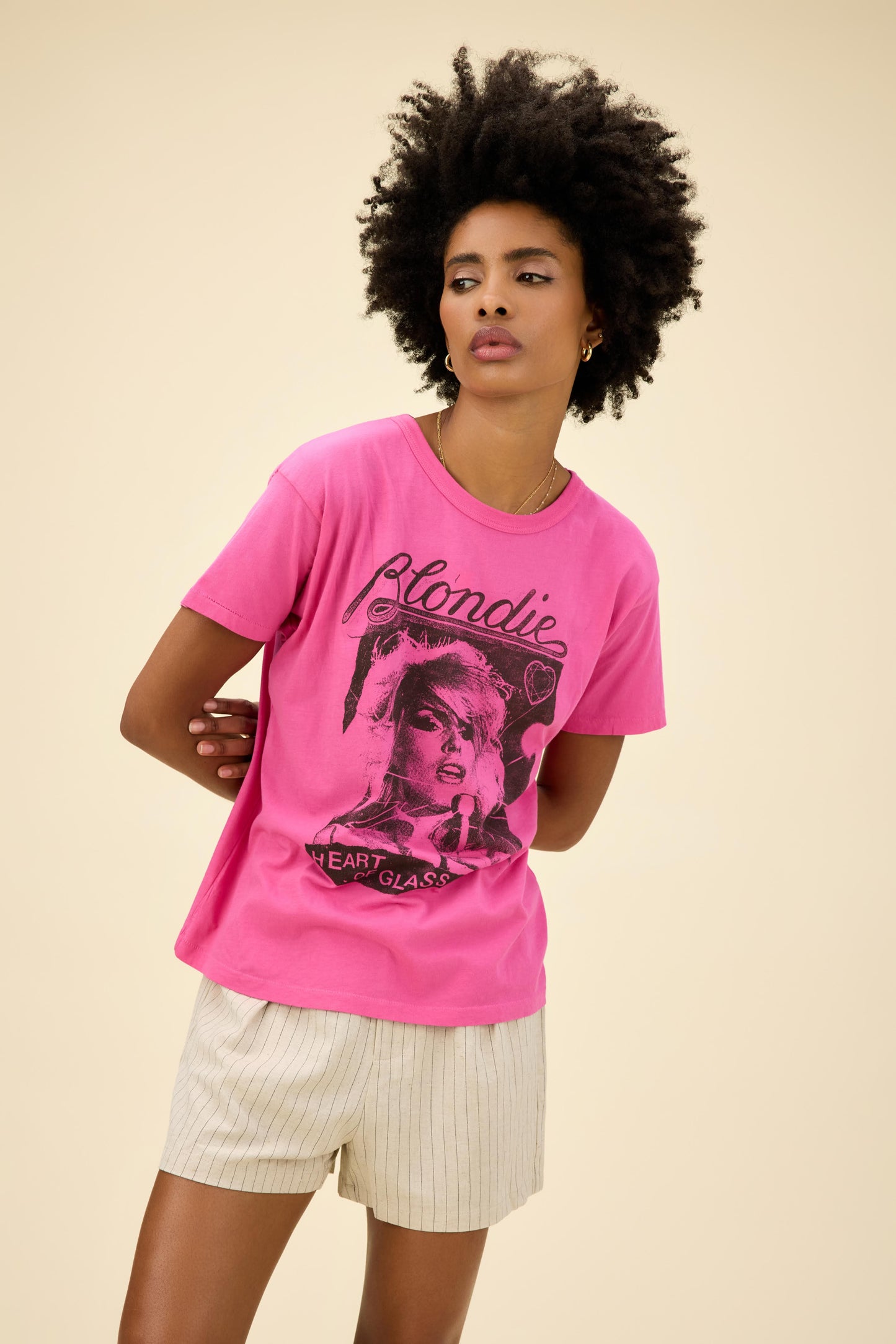 Curly-haired model wearing a Blondie graphic ringer tee in pink with 'Heart Of Glass' artwork on the front and back.