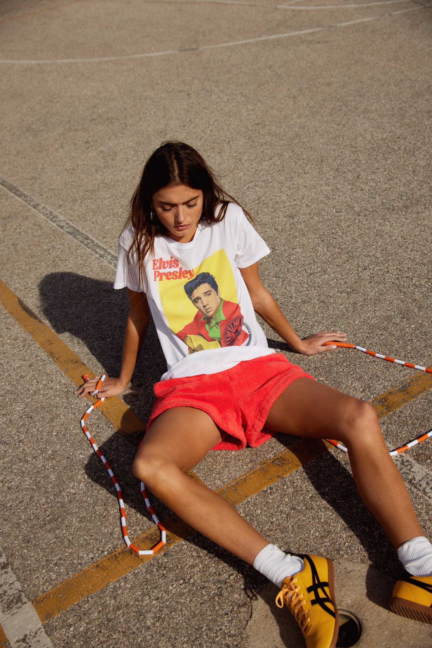 A model featuring a white tee stamped with "Elvis presley" and designed with a portrait of the artist itself.