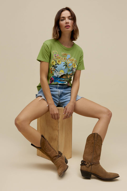 A model featuring a matcha ringer tee stamped with 'The Beach Boys', with their graphic beach logo.