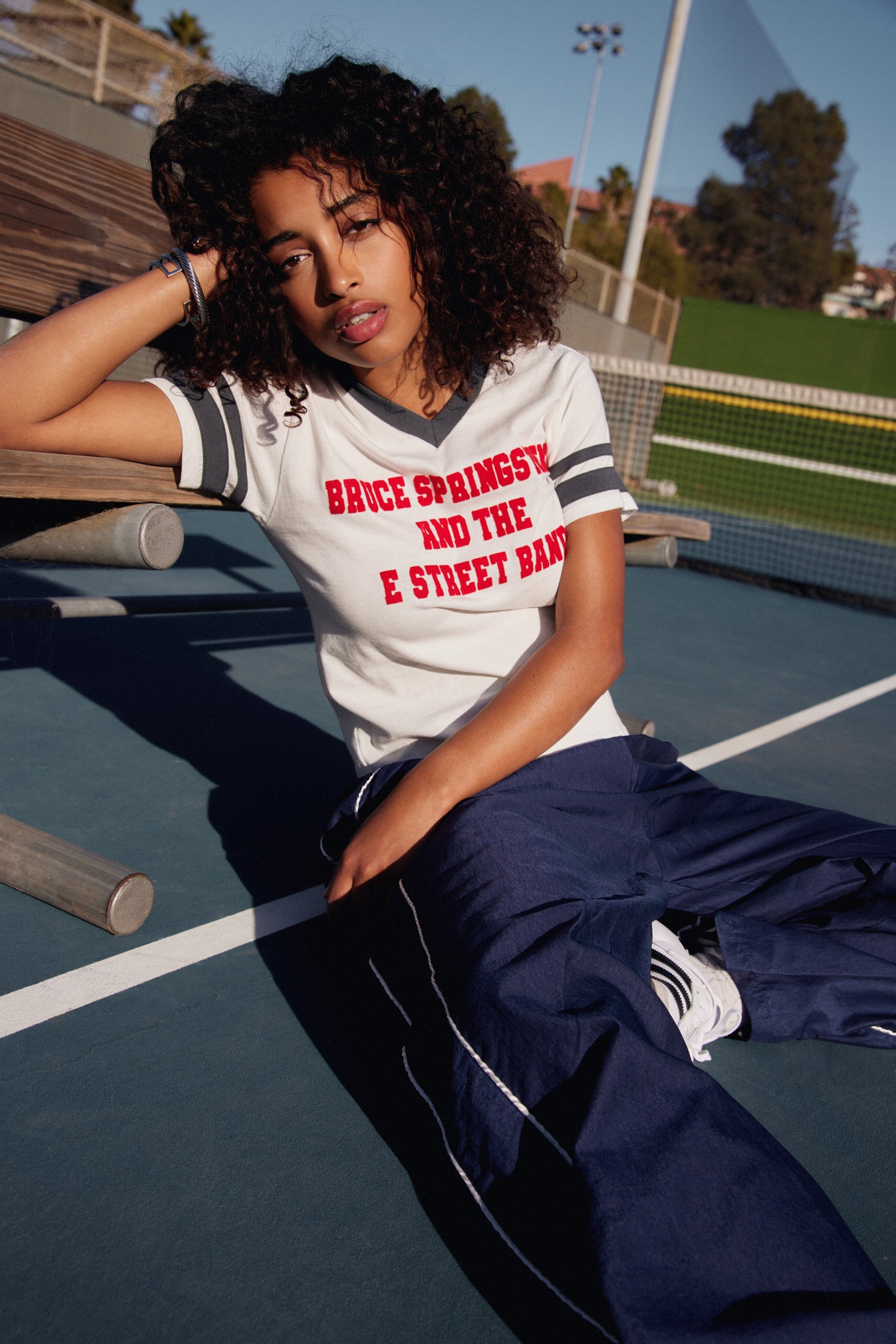 A model featuring a white sporty tee with black stripes on the sleeves.