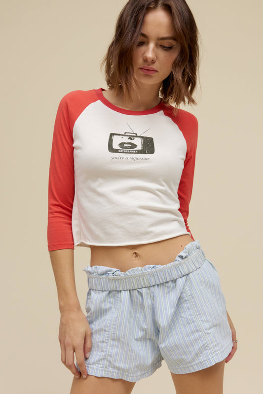 A model featuring a white vintage raglan with red sleeves and a graphic tv in front.