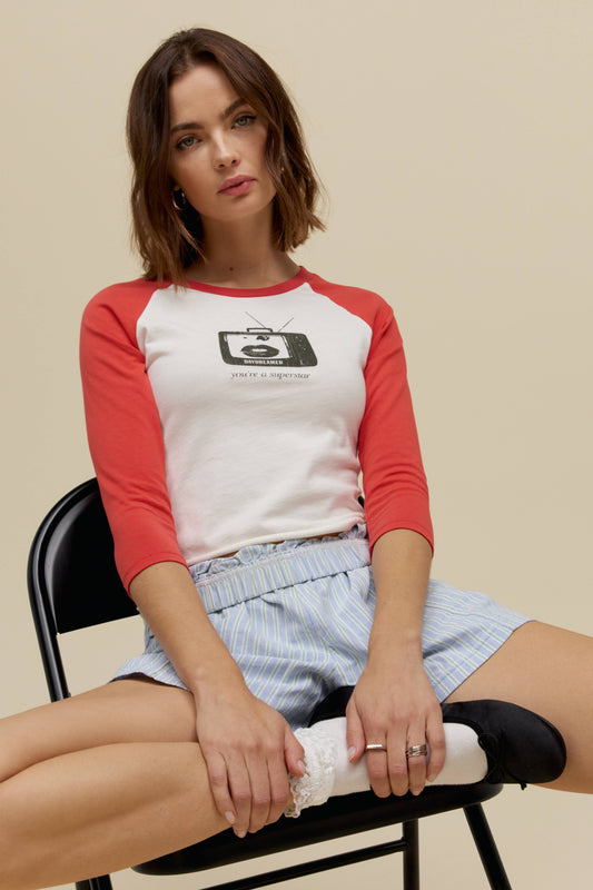 A model featuring a white vintage raglan with red sleeves and a graphic tv in front.