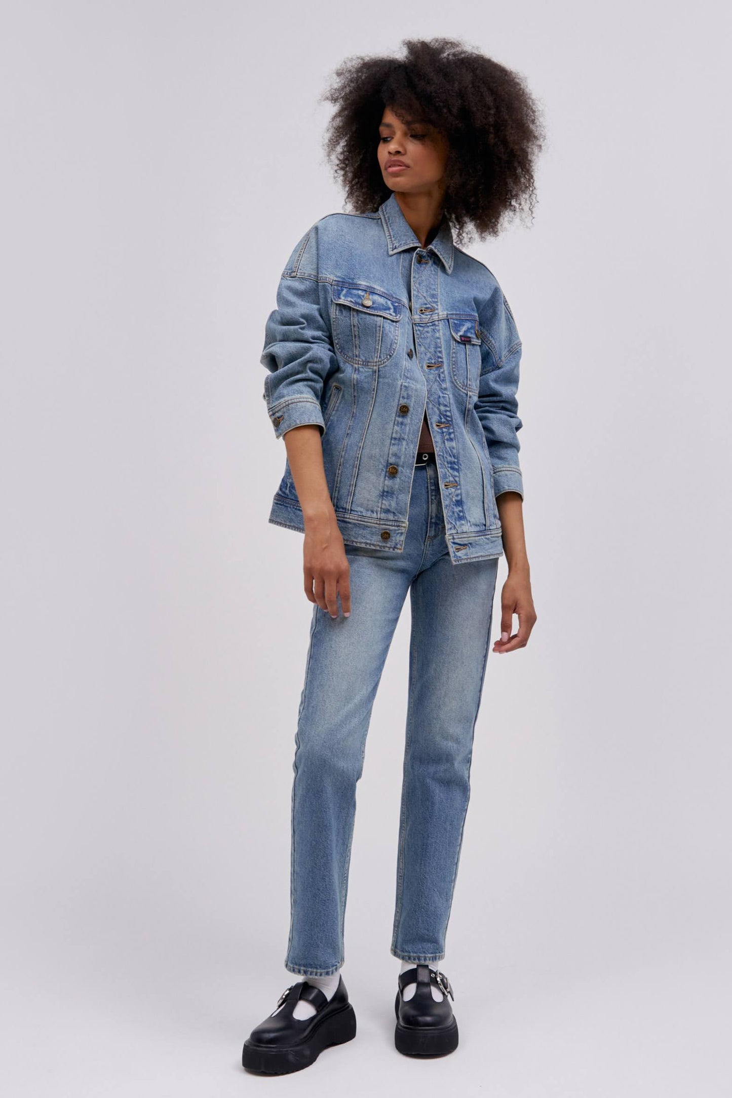 Curly haired model wearing a reimagined Lee Denim rider jacket in an oversized fit.