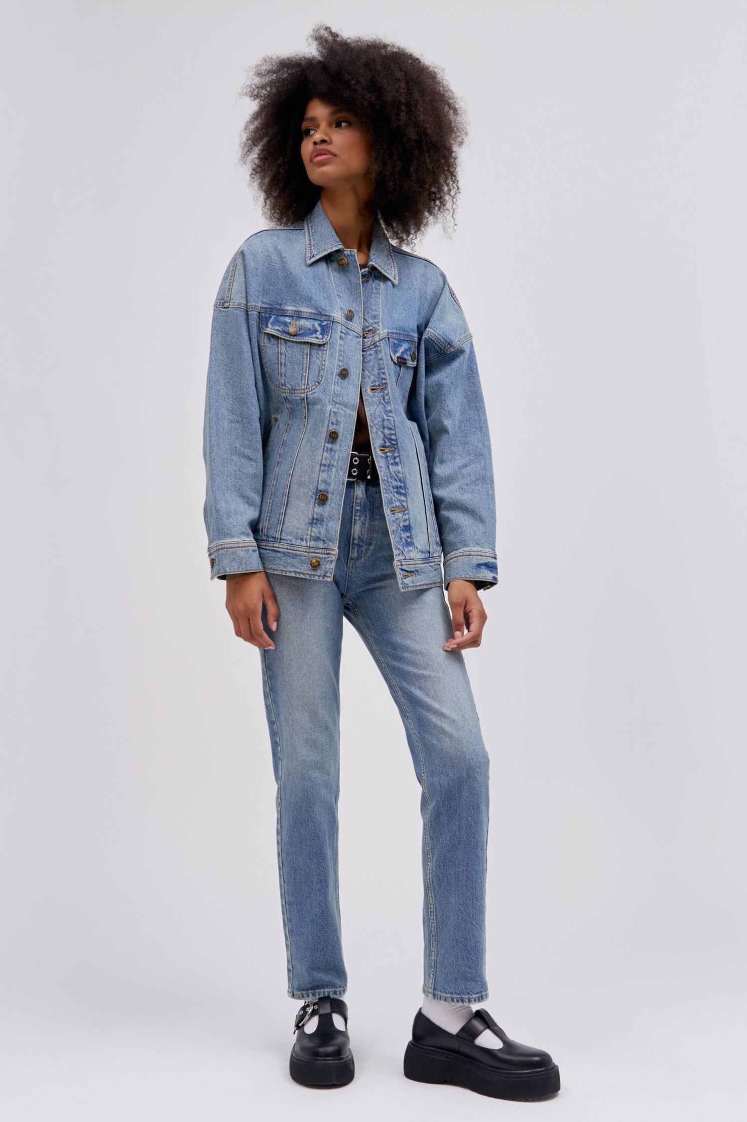 Curly haired model wearing a reimagined Lee Denim rider jacket in an oversized fit.