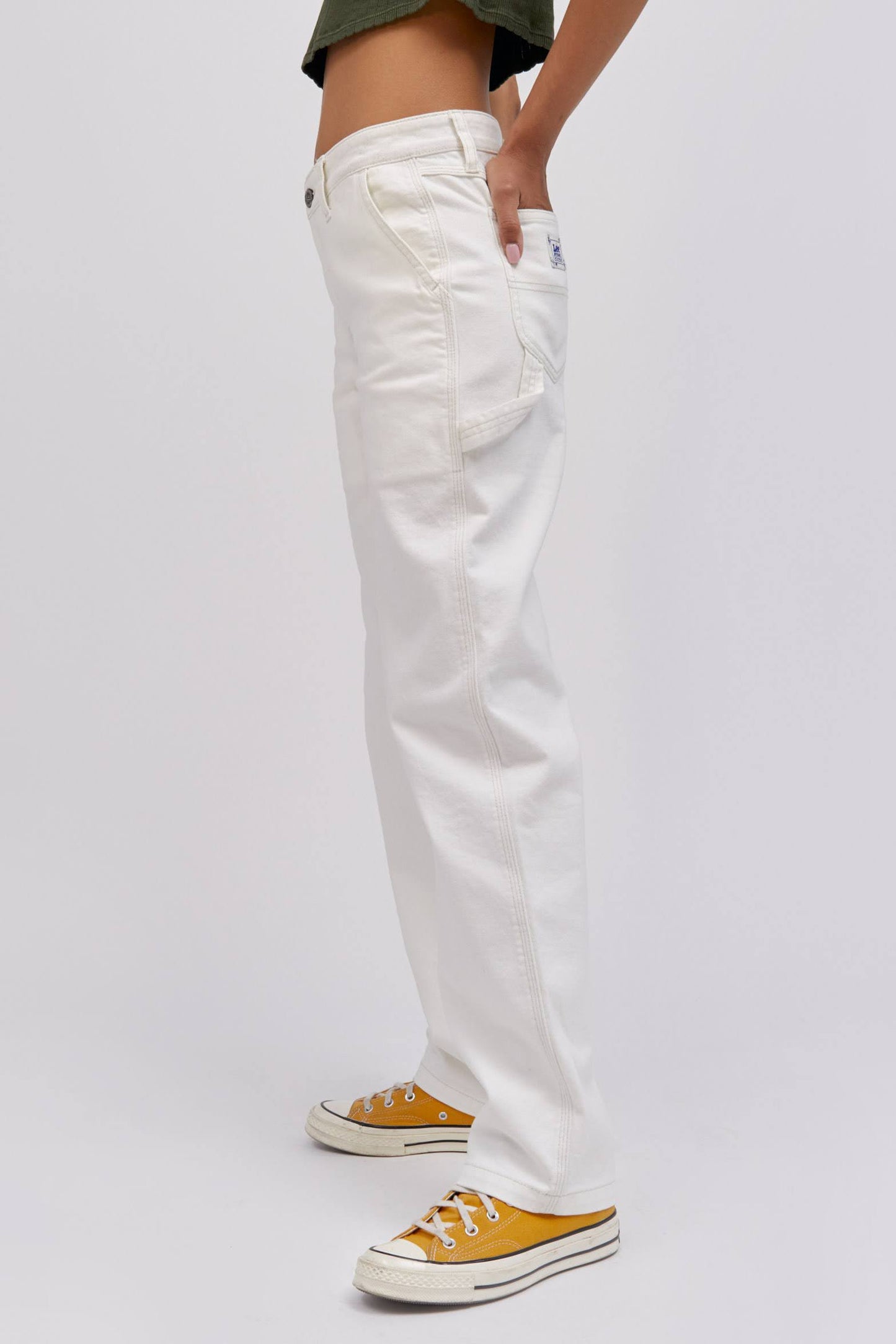 A  model featuring a white workwear pant made from heavy cotton, accented with key Lee detailing of triple-stitched seams, oversized pockets and a uniform like hammer loop.