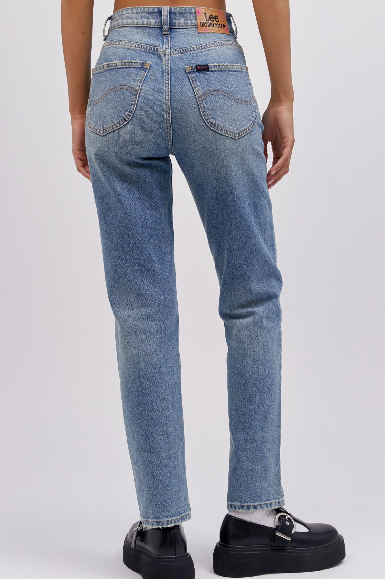 A model featuring a mid storm colored high rise and straight-legged jeans with a slim fit through the hips.