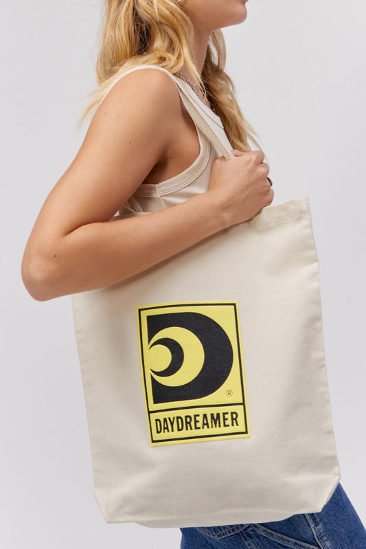 GIRL HOLDING CANVAS TOTE WITH YELLOW DAYDREAMER LOGO