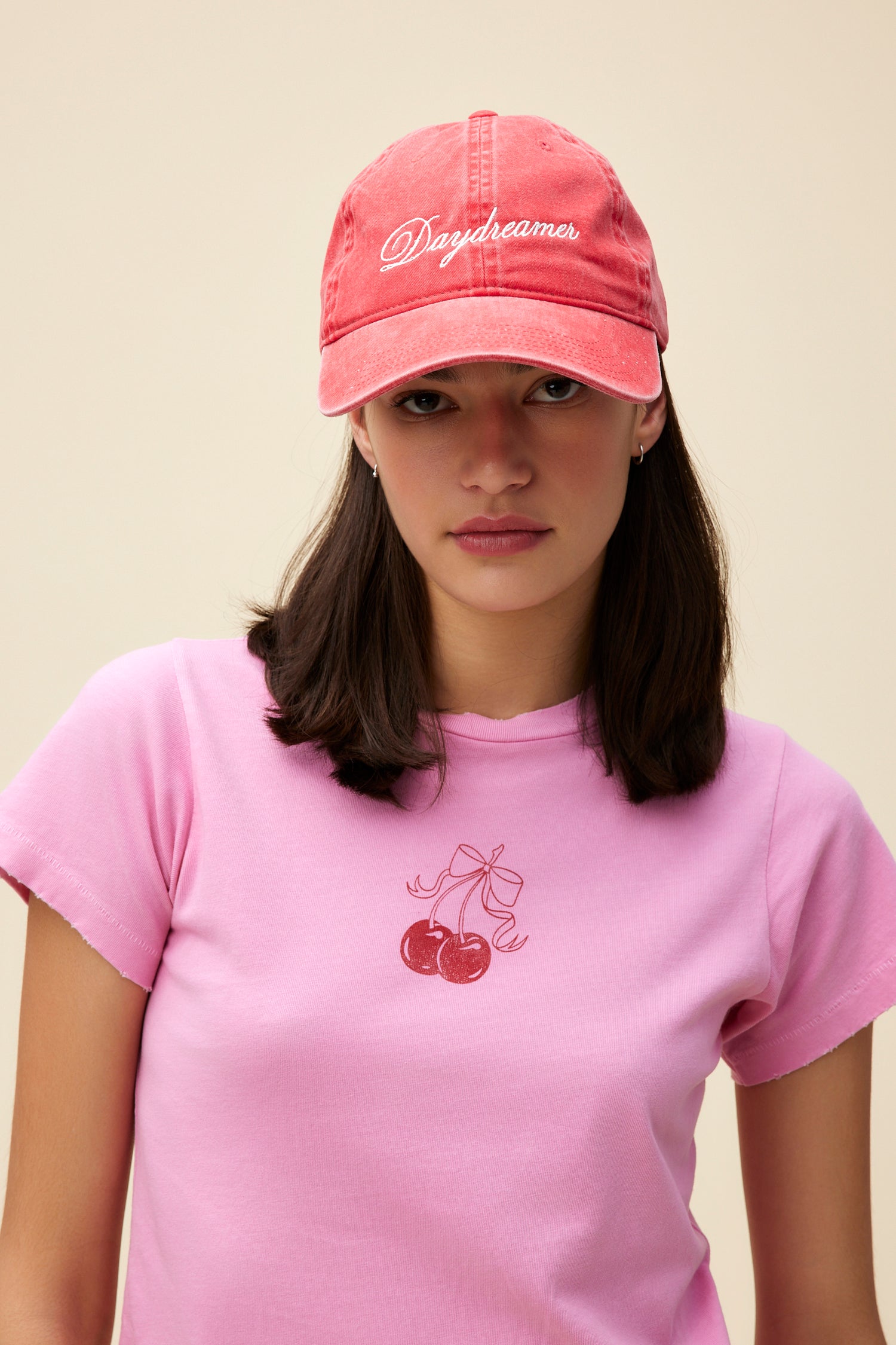 Model wearing a washed red denim dad hat with 'Daydreamer' logo script embroidered on the front.