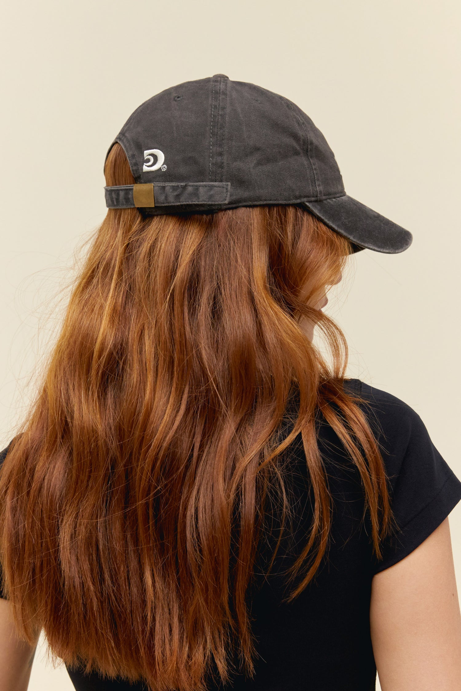 Model wearing a washed black dad hat with Daydreamer logo embroidery on the front and back.
