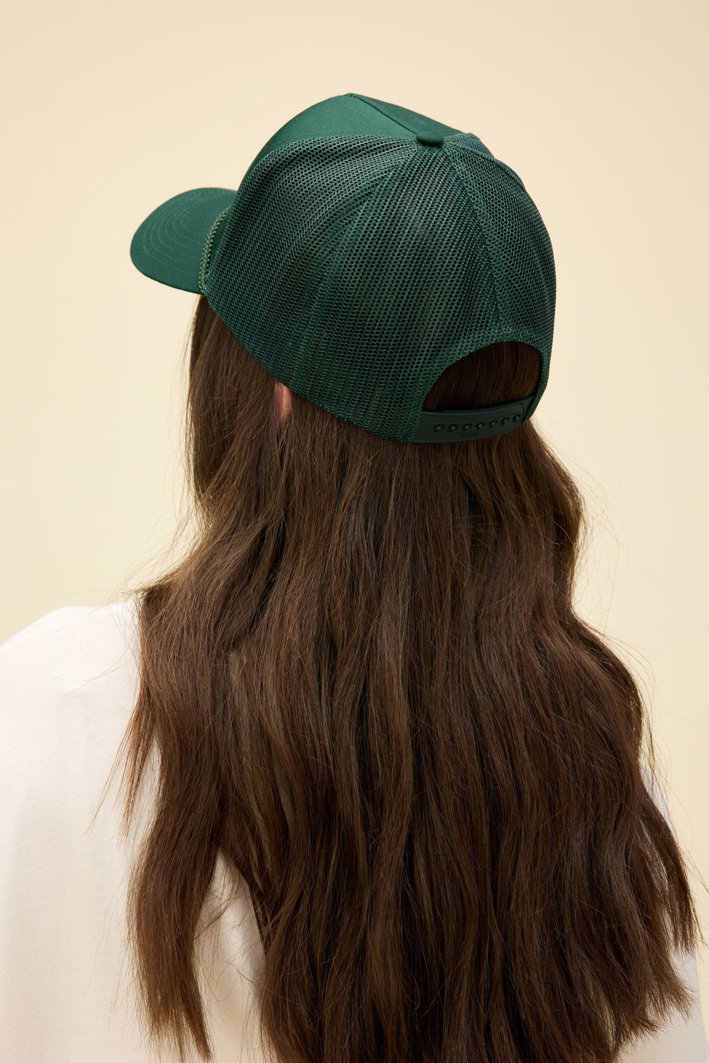 Model wearing a dark green trucker hat with western-style 'Daydreamer Studios' embroidery on the front.
