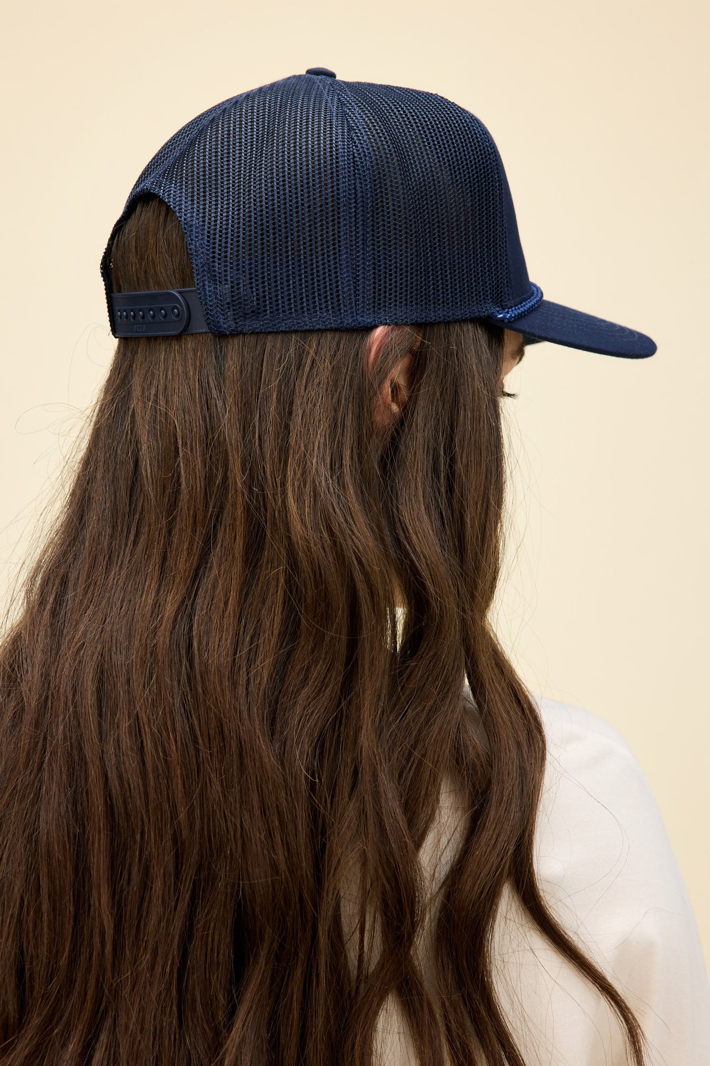 Model wearing a navy blue trucker hat with western-style 'Daydreamer Studios' embroidery on the front.