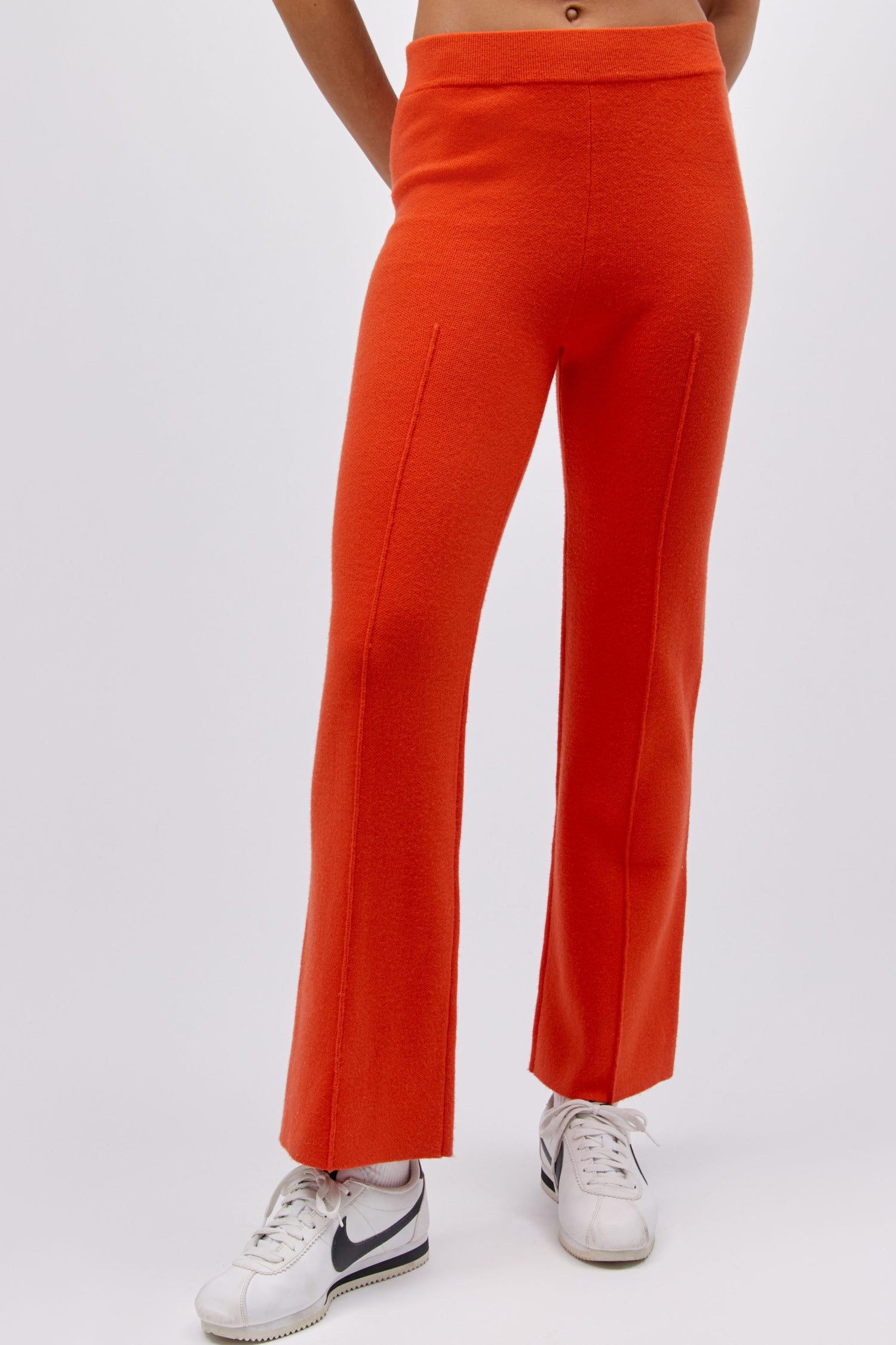 A model featuring a hot orange pintuck pant.