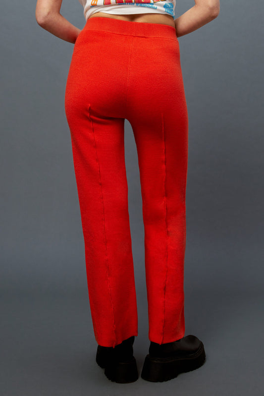 Model wearing a pair of knit pintuck pants in hot orange