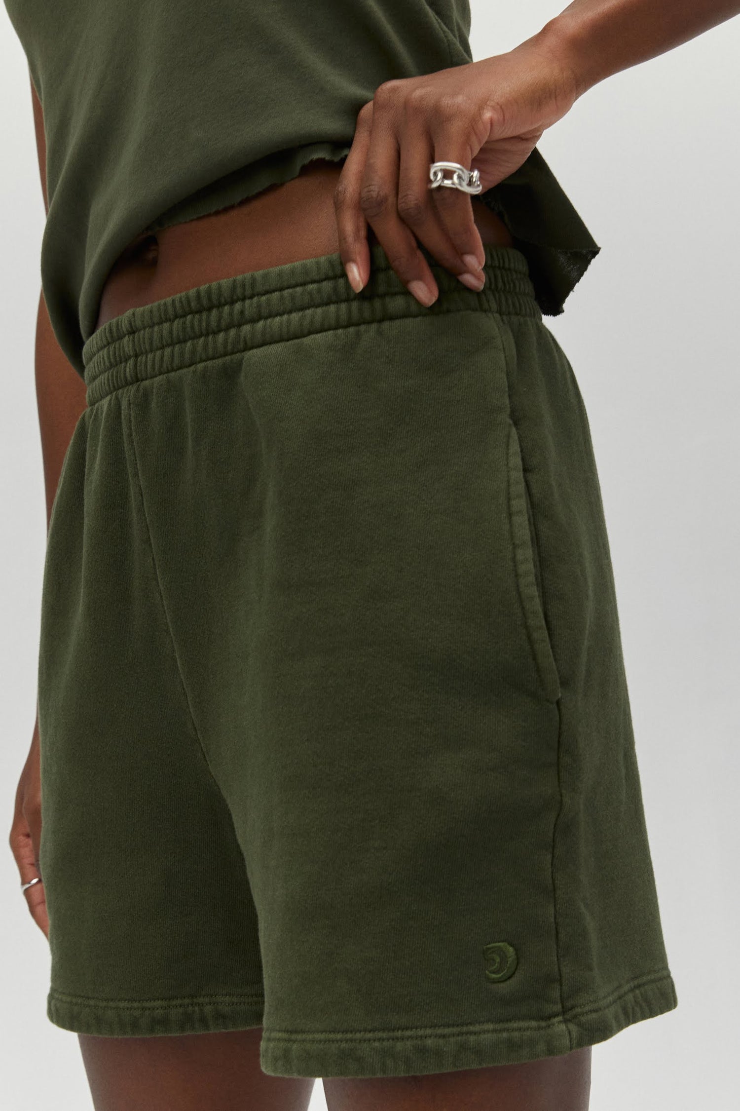 Model wearing boyfriend fitting sweat shorts in military green with a matching tank top.