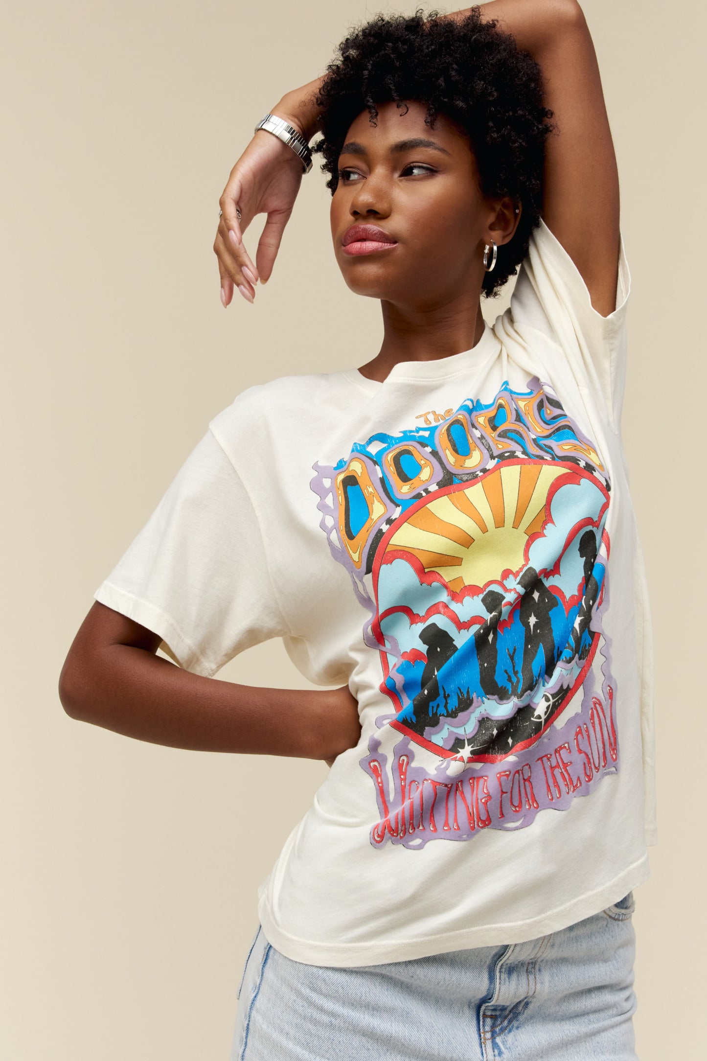 A model featuring a white tee designed with an exclusive rendition of The Door’s lead members at sunrise, inspired by the album’s original cover.