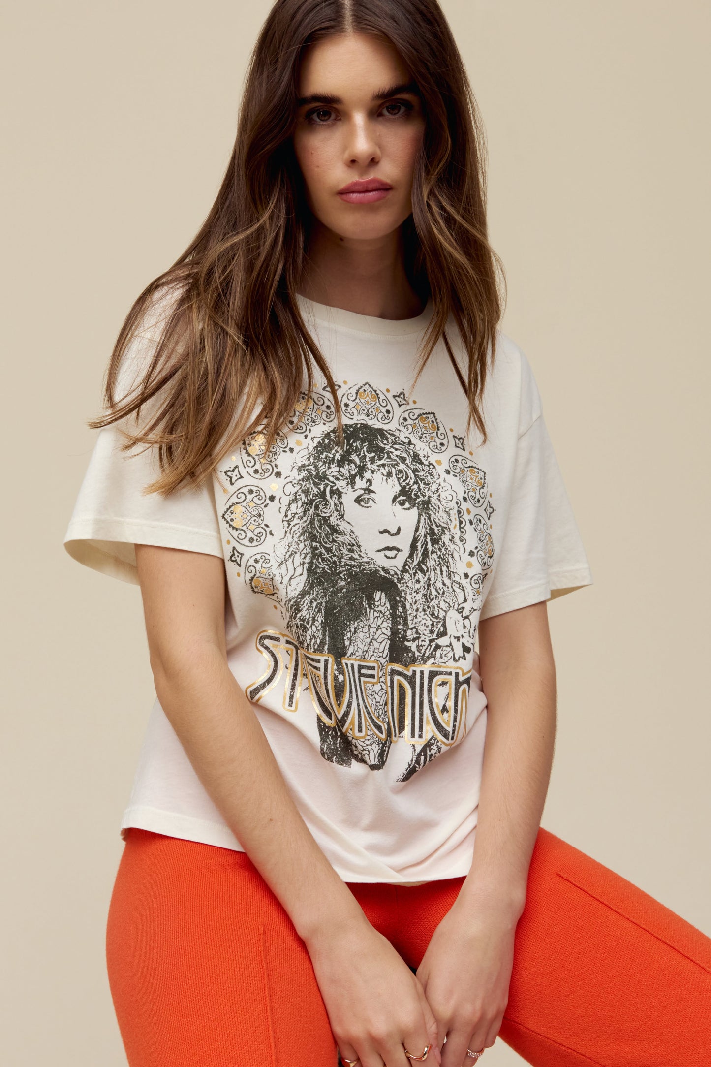 A model featuring a white tee designed with a portrait fit to represent the icon’s free-spirited energy and 70s bohemian style lands center accented in metallic ink.