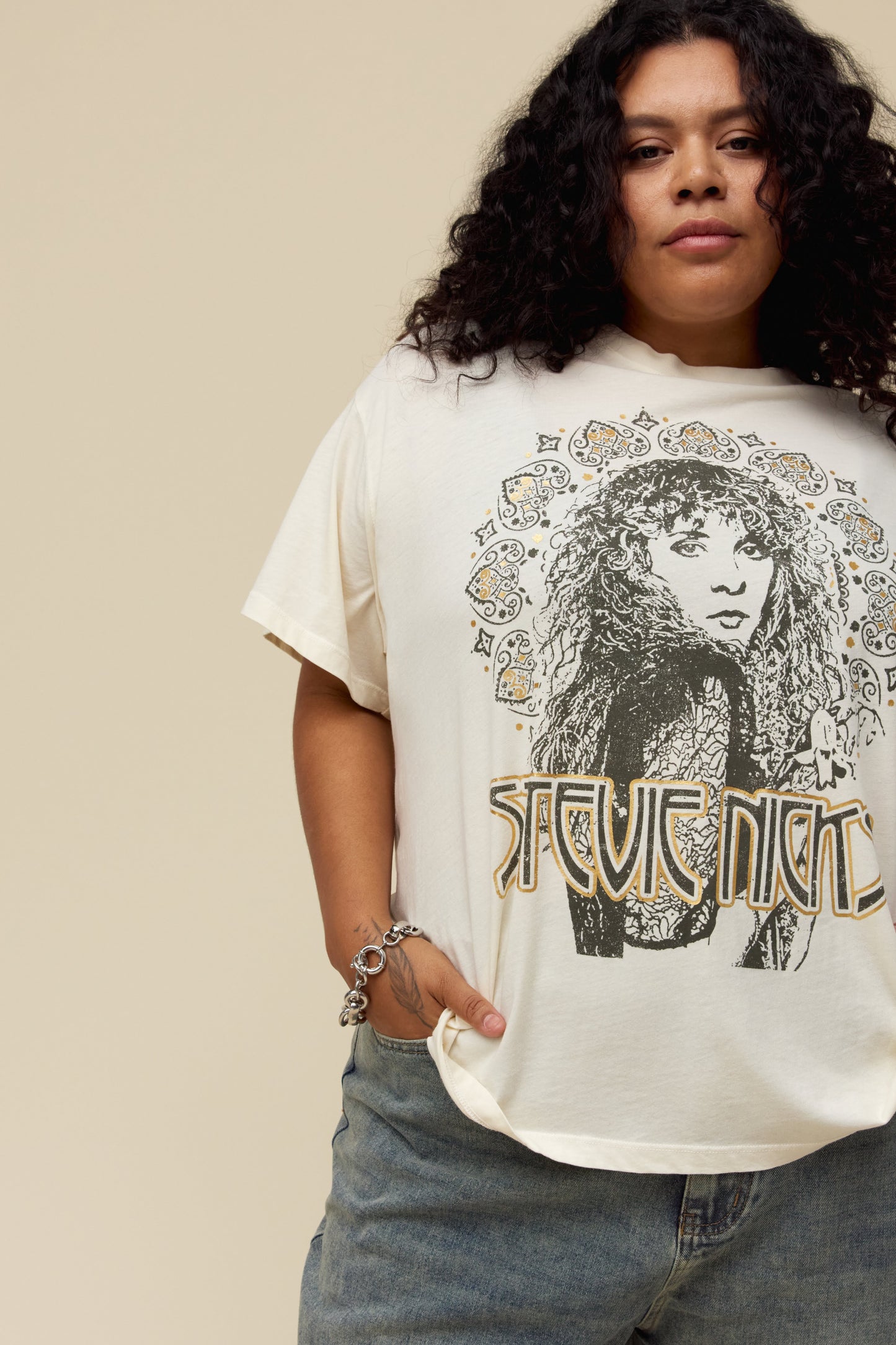 A model featuring a white tee es designed with a portrait fit to represent the icon’s free-spirited energy and 70s bohemian style lands center accented in metallic ink.