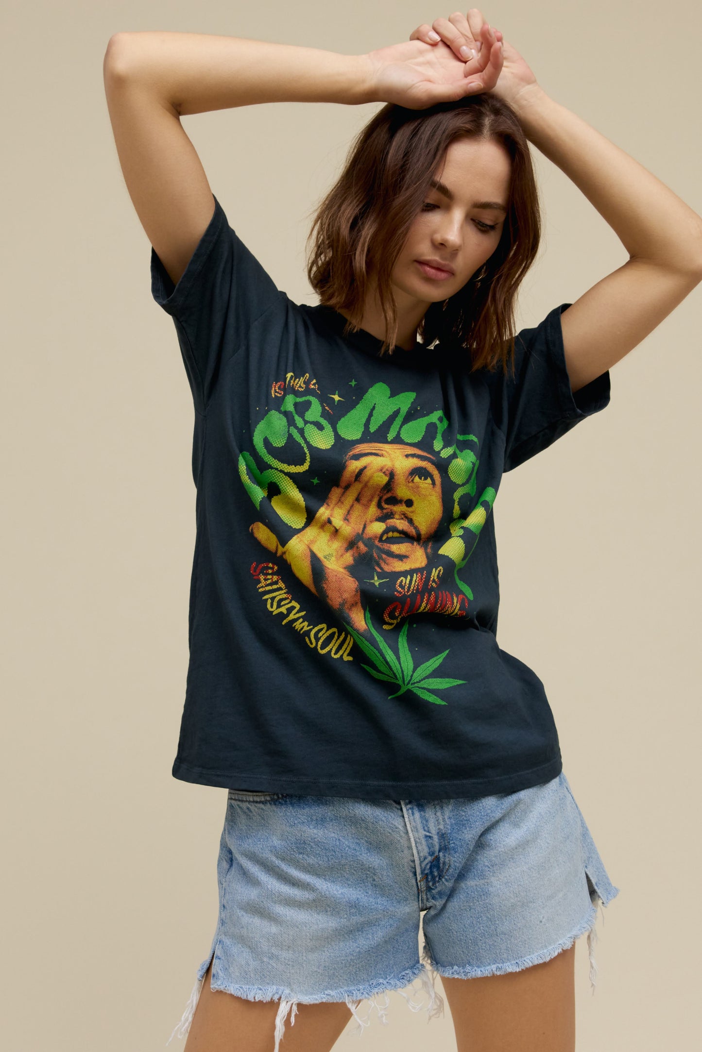 Short-haired model wearing a Bob Marley tee in vintage black featuring graphics of his hit song titles