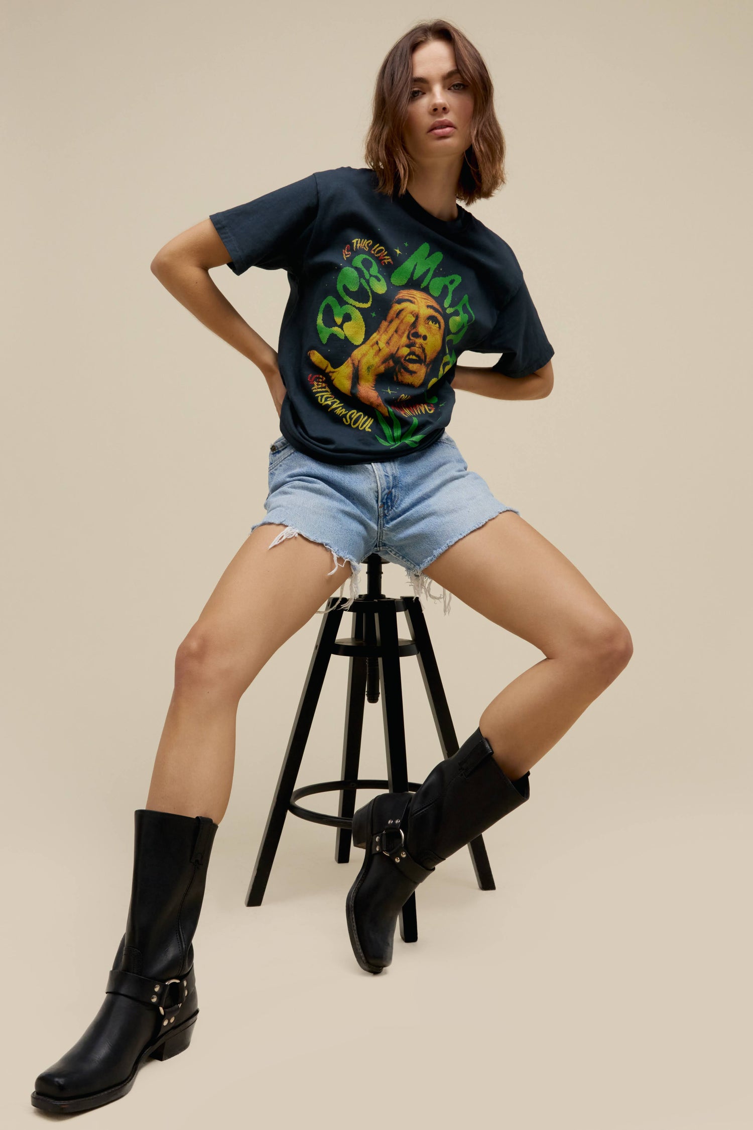 Short-haired model wearing a Bob Marley tee in vintage black featuring graphics of his hit song titles