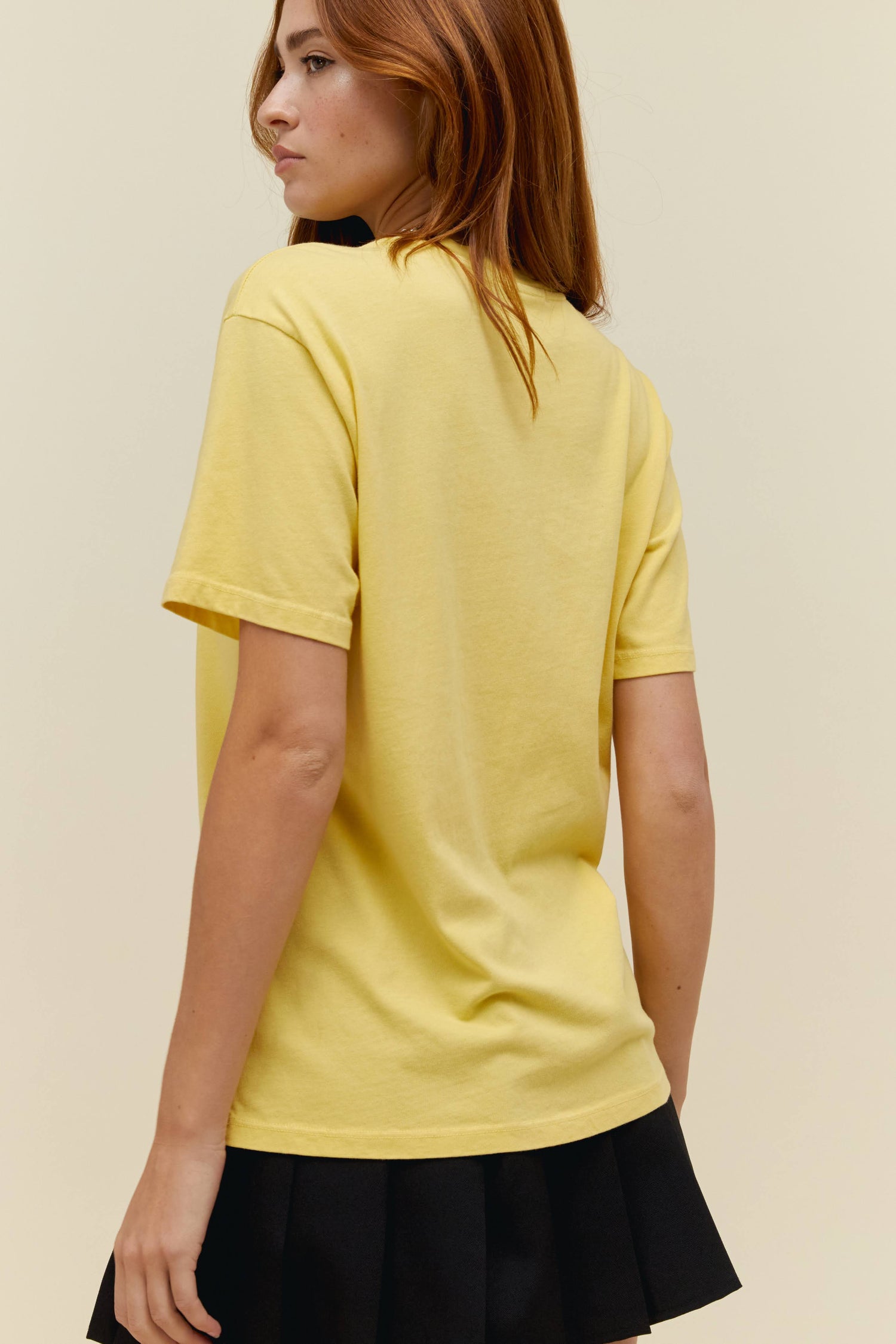 A model featuring a yellow weekend tee designed with flowers in the muddke and stamped with 'Guns N' Roses'