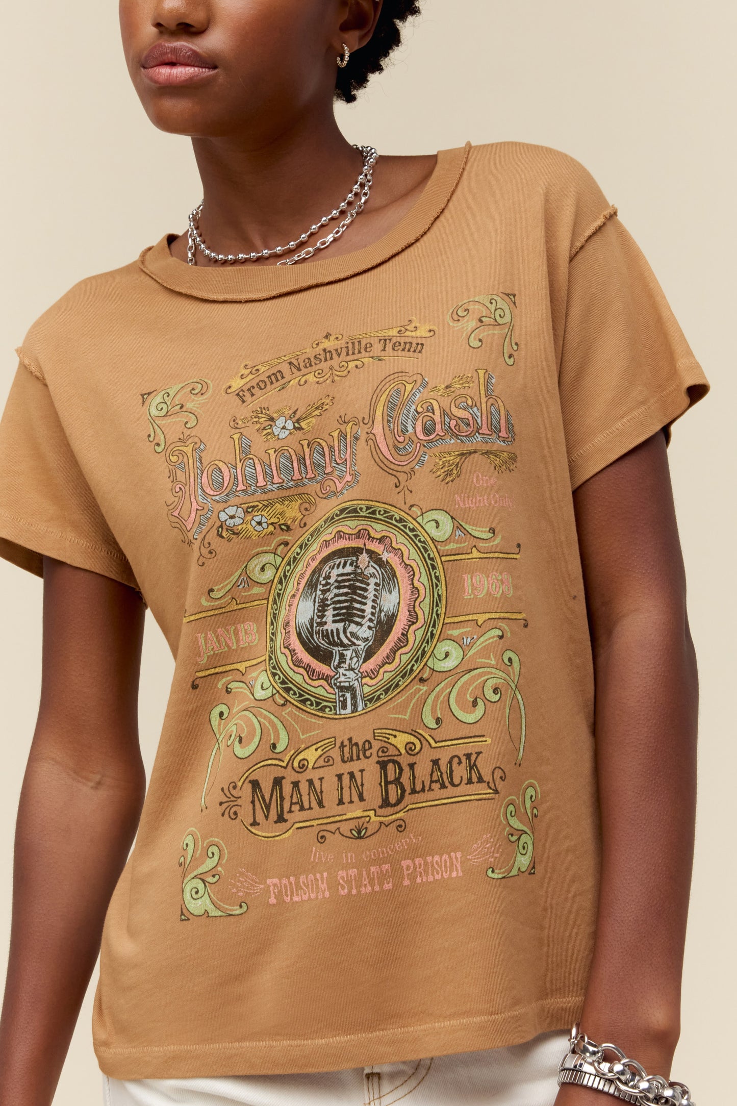 A model featuring a hazelnut colored Johnny Cash gf tee stamped with "Man in Black" and a microphone label placing spotlight on “Johnny Cash at Folsom Prison”.