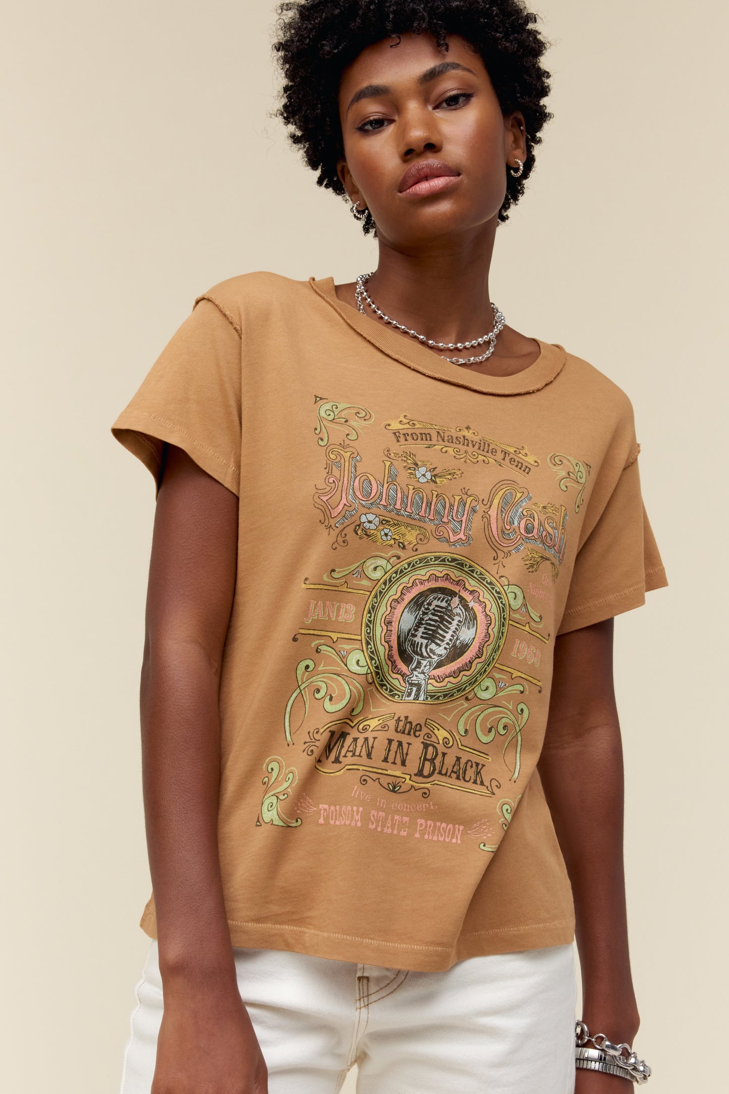 A model featuring a hazelnut colored Johnny Cash gf tee stamped with "Man in Black" and a microphone label placing spotlight on “Johnny Cash at Folsom Prison”.