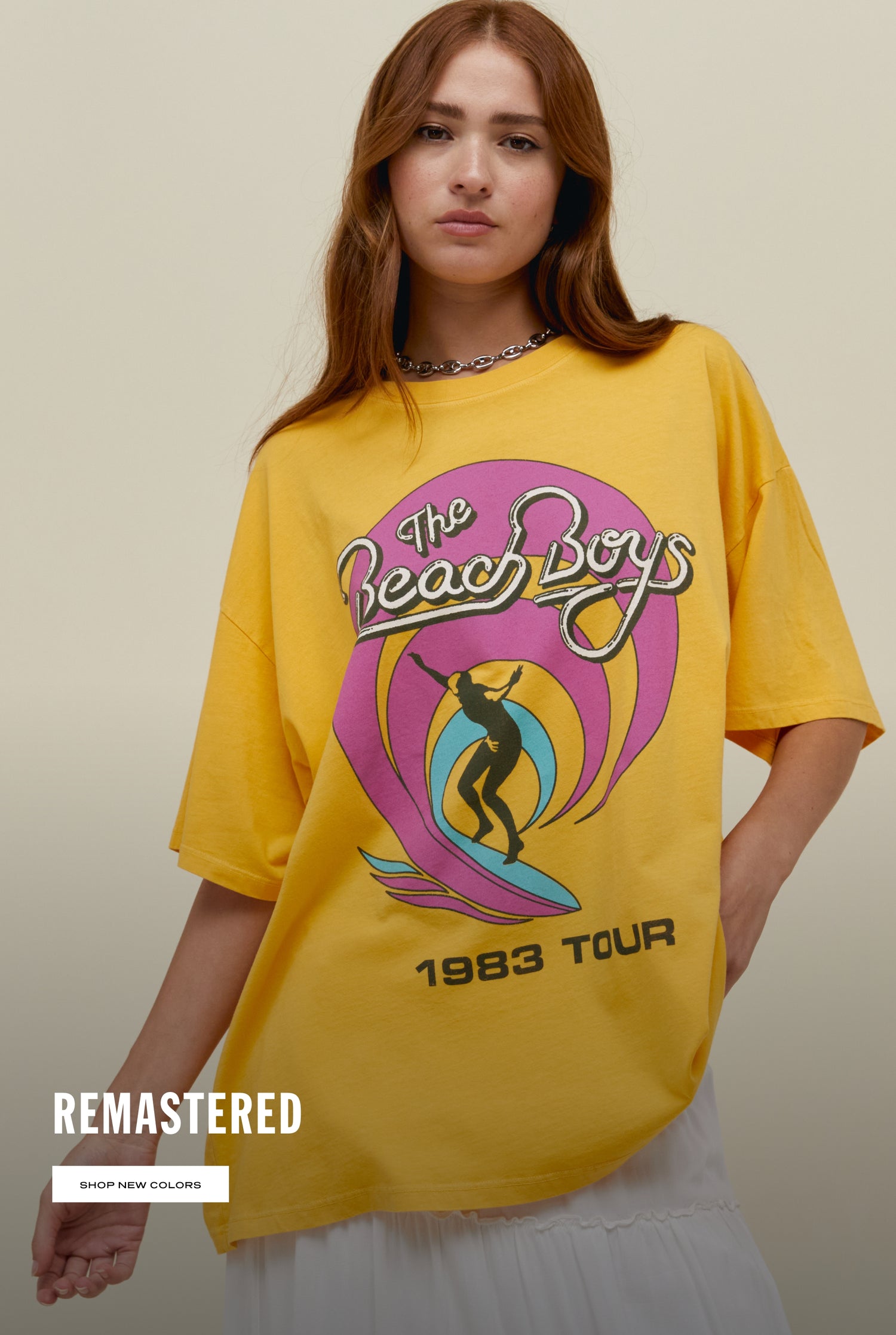 Straight haired model wearing The Beach Boys 1983 Tour oversized graphic tee in yellow.