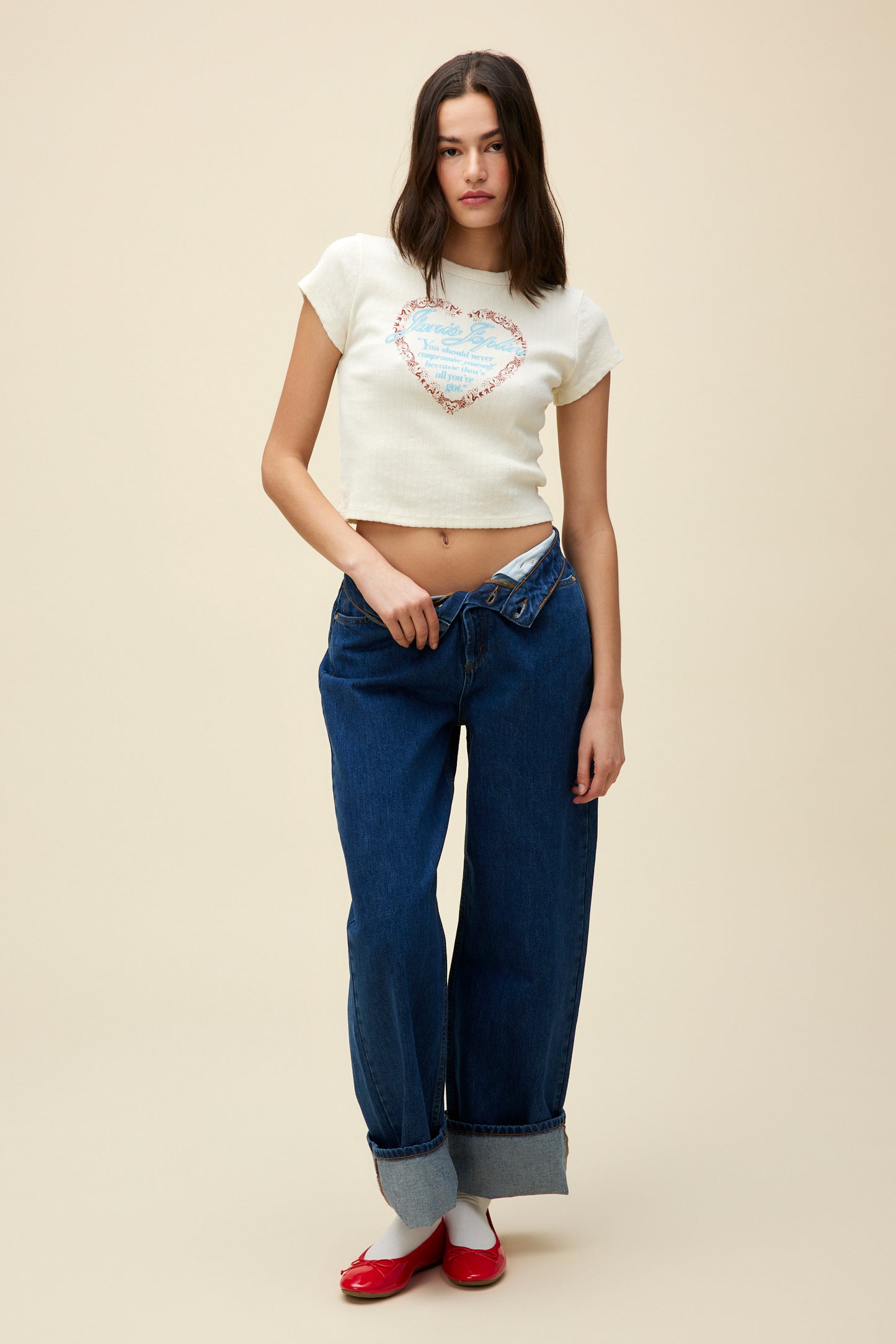 A model featuring a stone vintage baby tee featuring a red lace heart with Janis Joplin’s legendary ‘never compromise’ quote written in blue on the center. 