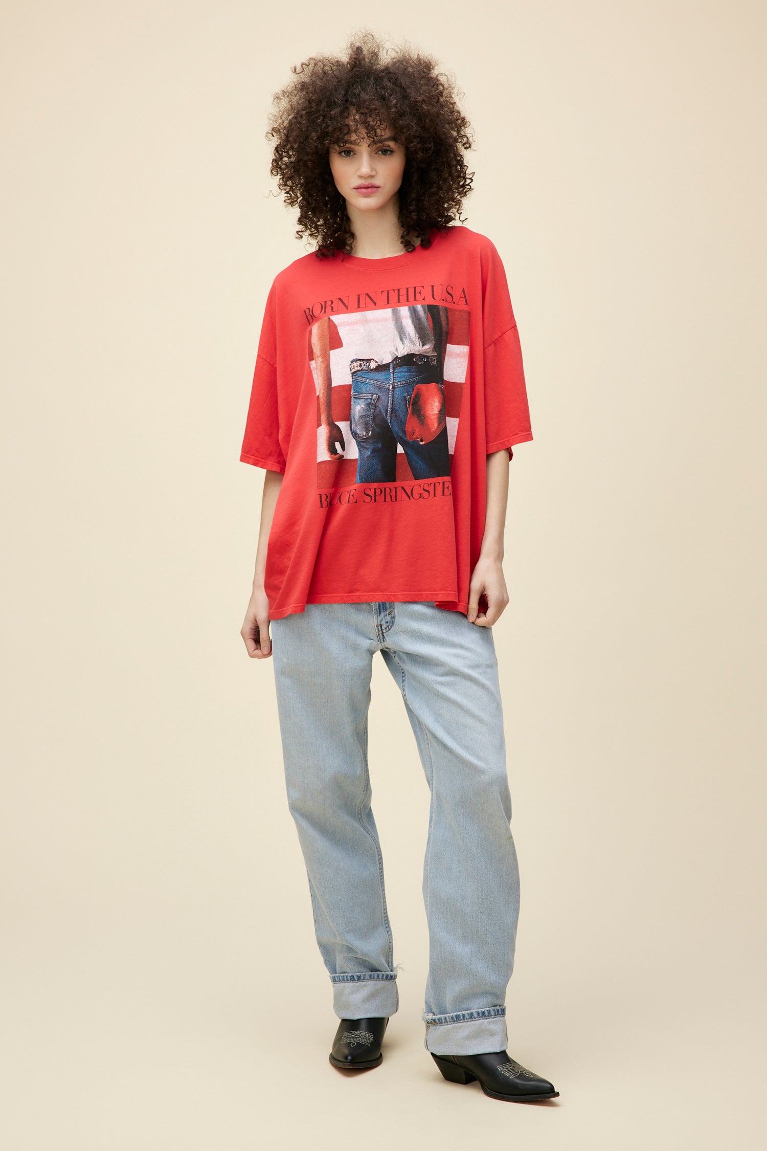 A  model featuring a red one-size shirt designed with the graphics inspired by Bruce Springsteen's "Born in the USA" album art.
