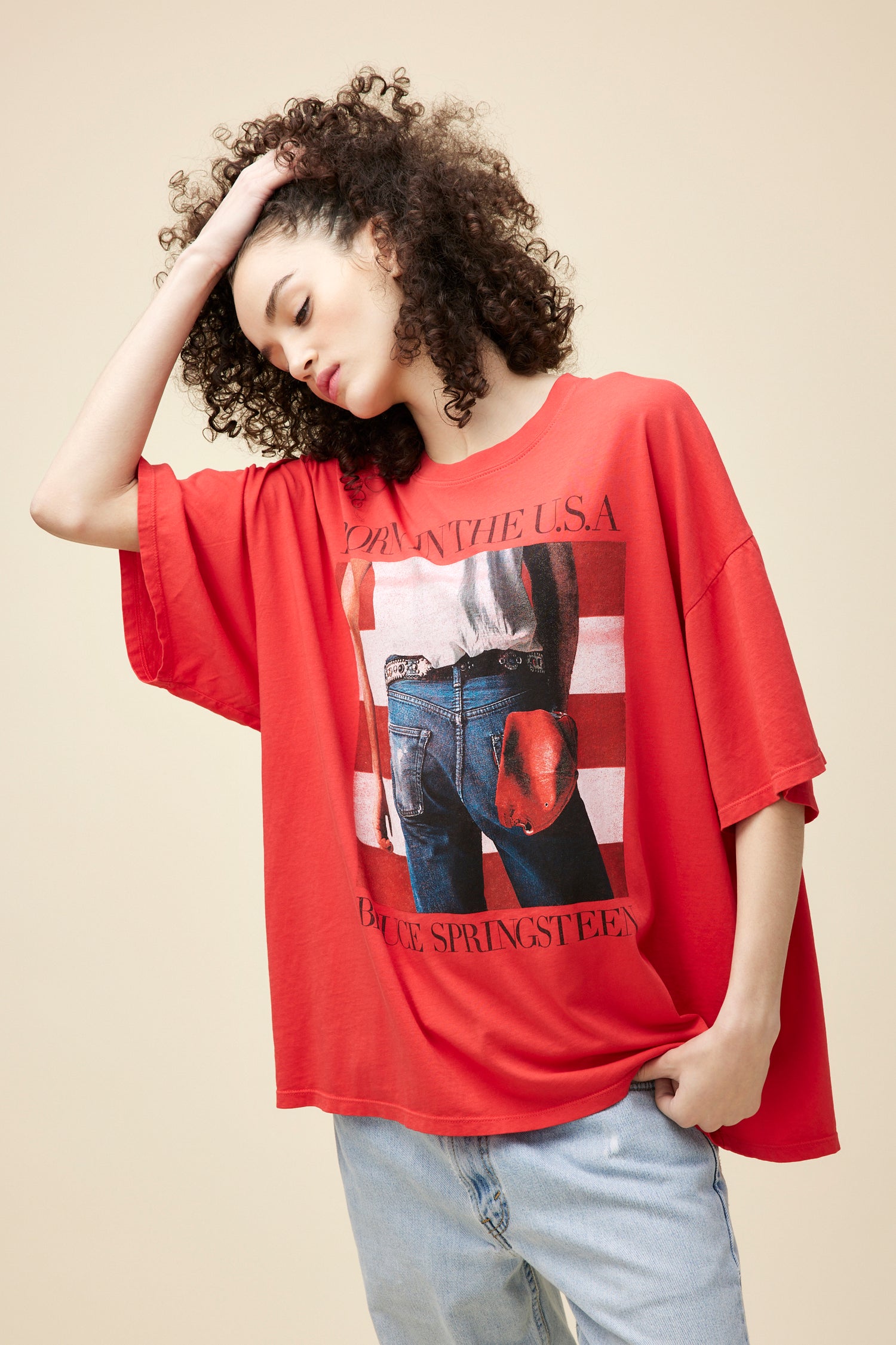 A  model featuring a red one-size shirt designed with the graphics inspired by Bruce Springsteen's "Born in the USA" album art.