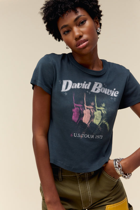 A model featuring a vintage black David Bowie shrunken tee designed with a graphic of Bowie himself with his guitar and his tour locations marked on the back.