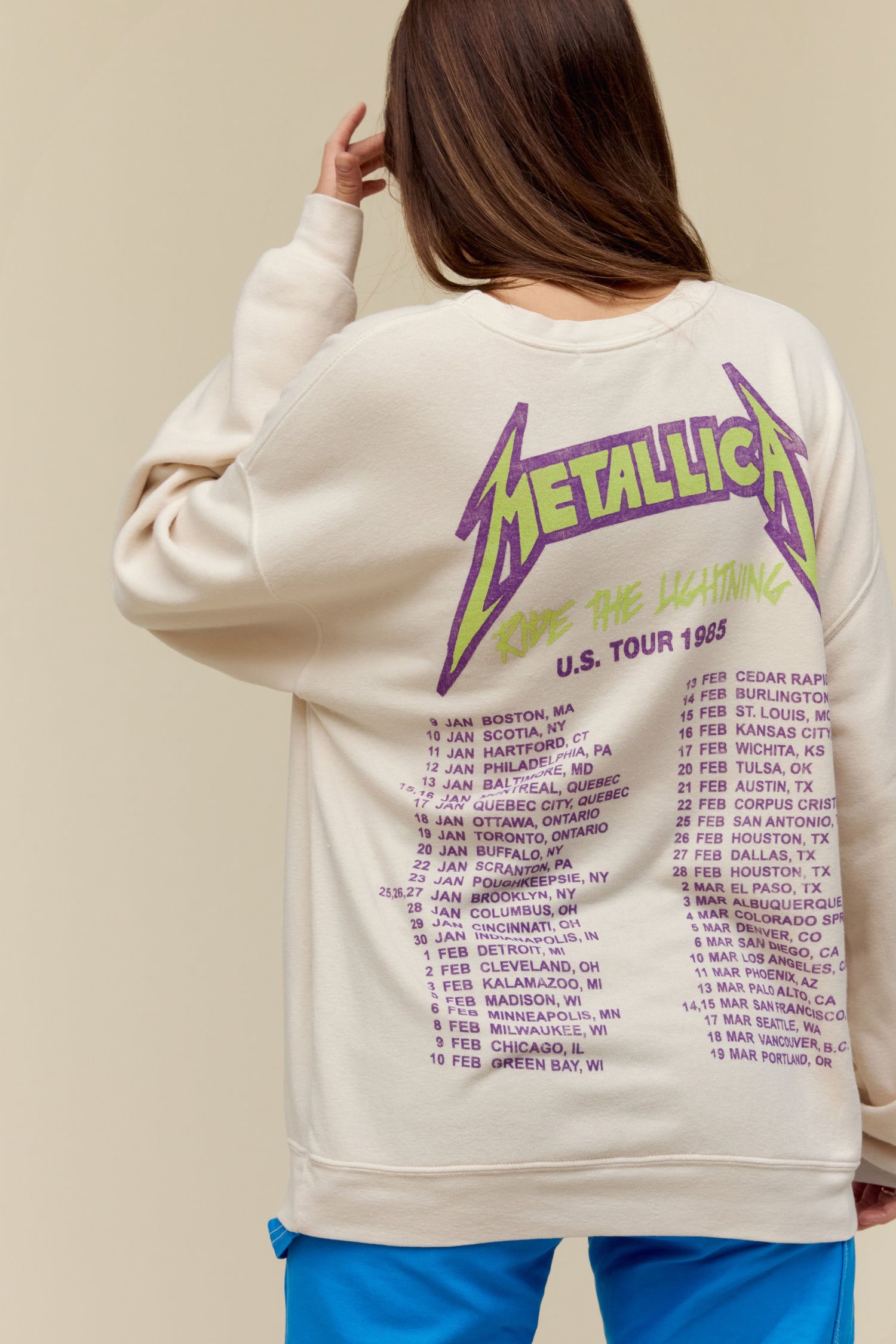 Model wearing a Metallica graphic crew sweatshirt with an oversized fit and 'Ride The Lightning' tour dates on the back.