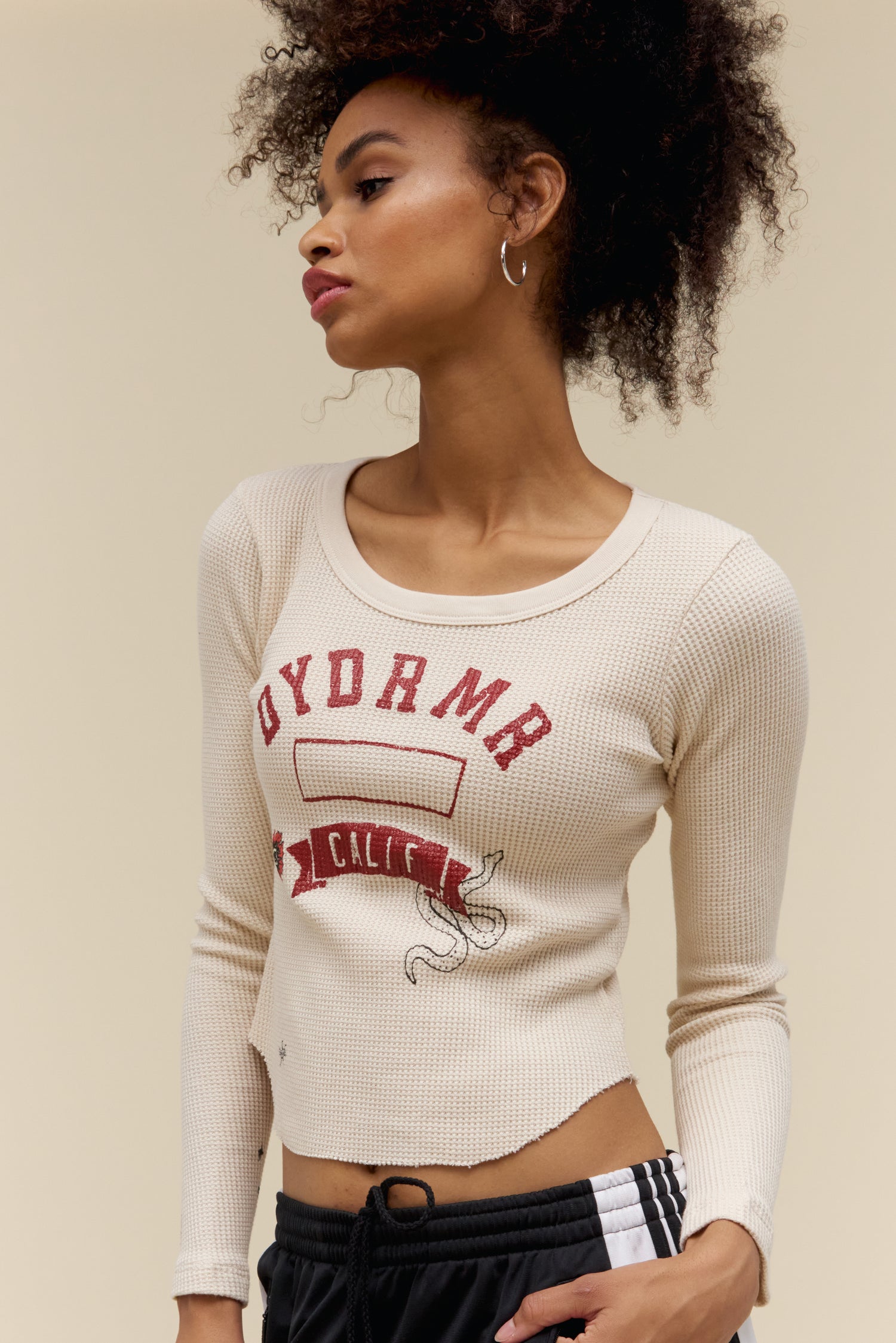 A model featuring a white fitted LS thermal stamped with DYDRMR and CALI in red font and a graphic skull on the back.