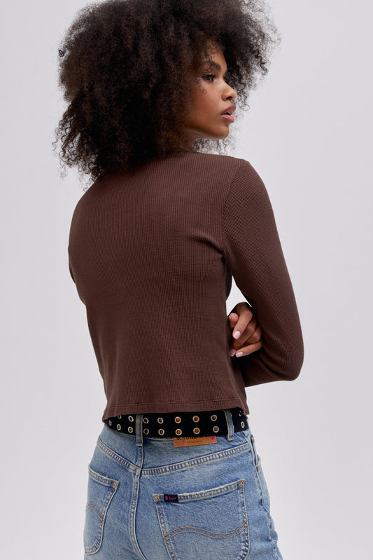 A curly-haired model featuring a coffee quarts colored shrunken thermal made with a slim fit, a cropped length, and designed with 'Daydreamer x Lee' in an original cut - paste style treatment accented with hand drawn graphic details.