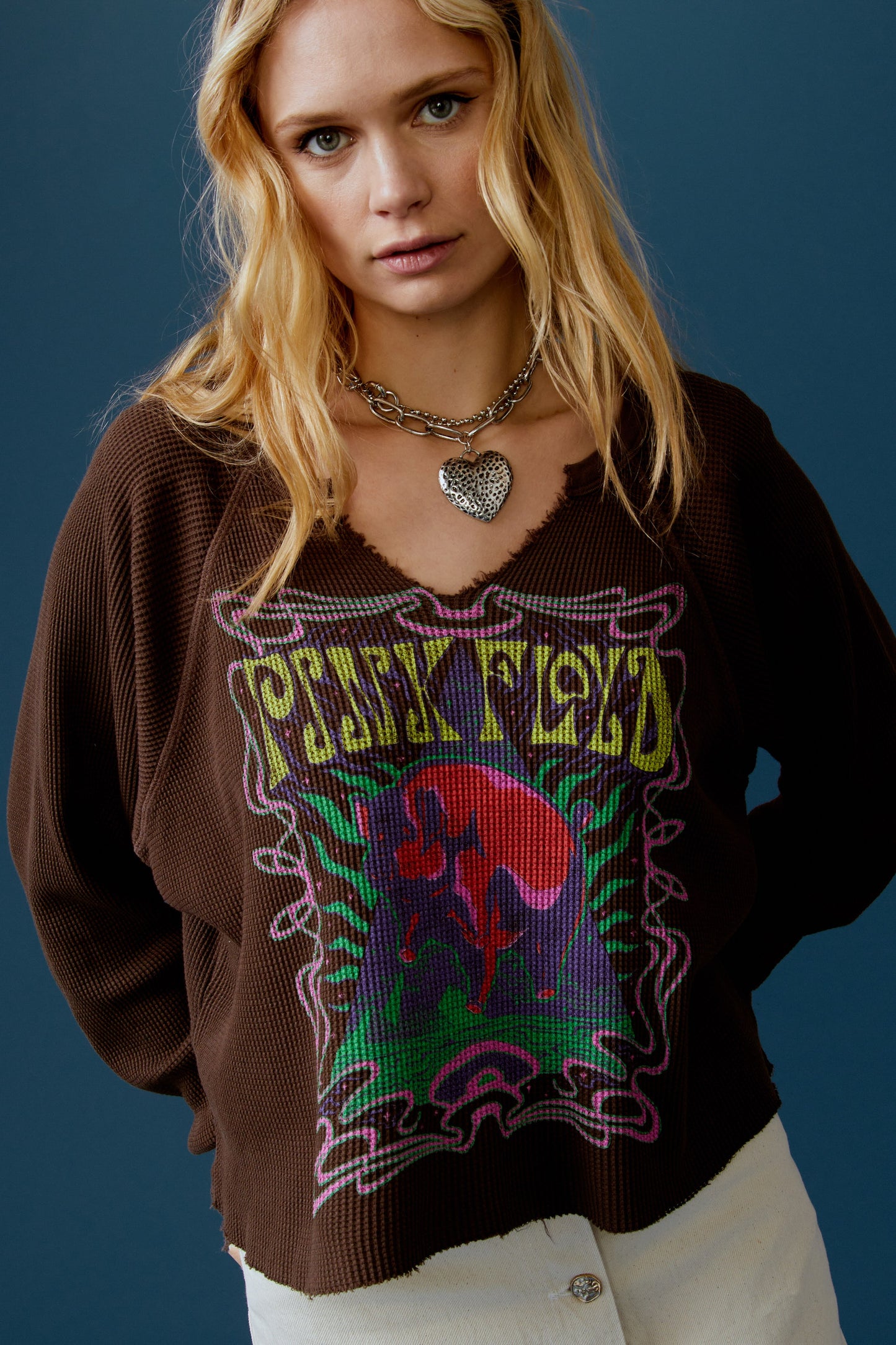 A blonde-haired model featuring a brown long sleeve stamped with 'Pink Floyd' in yellow font and a graphic of a cosmic pyramid.
