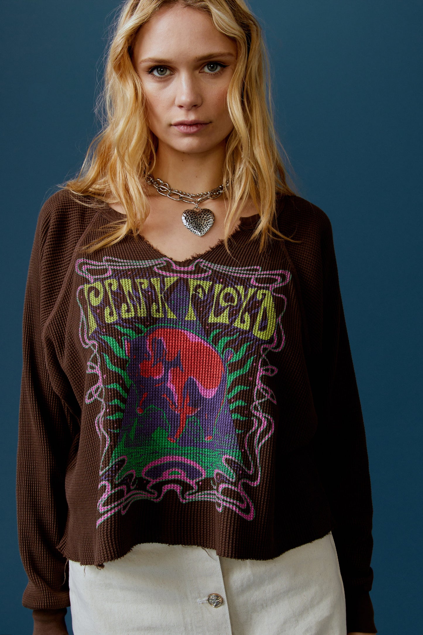 A blonde-haired model featuring a brown long sleeve stamped with 'Pink Floyd' in yellow font and a graphic of a cosmic pyramid.