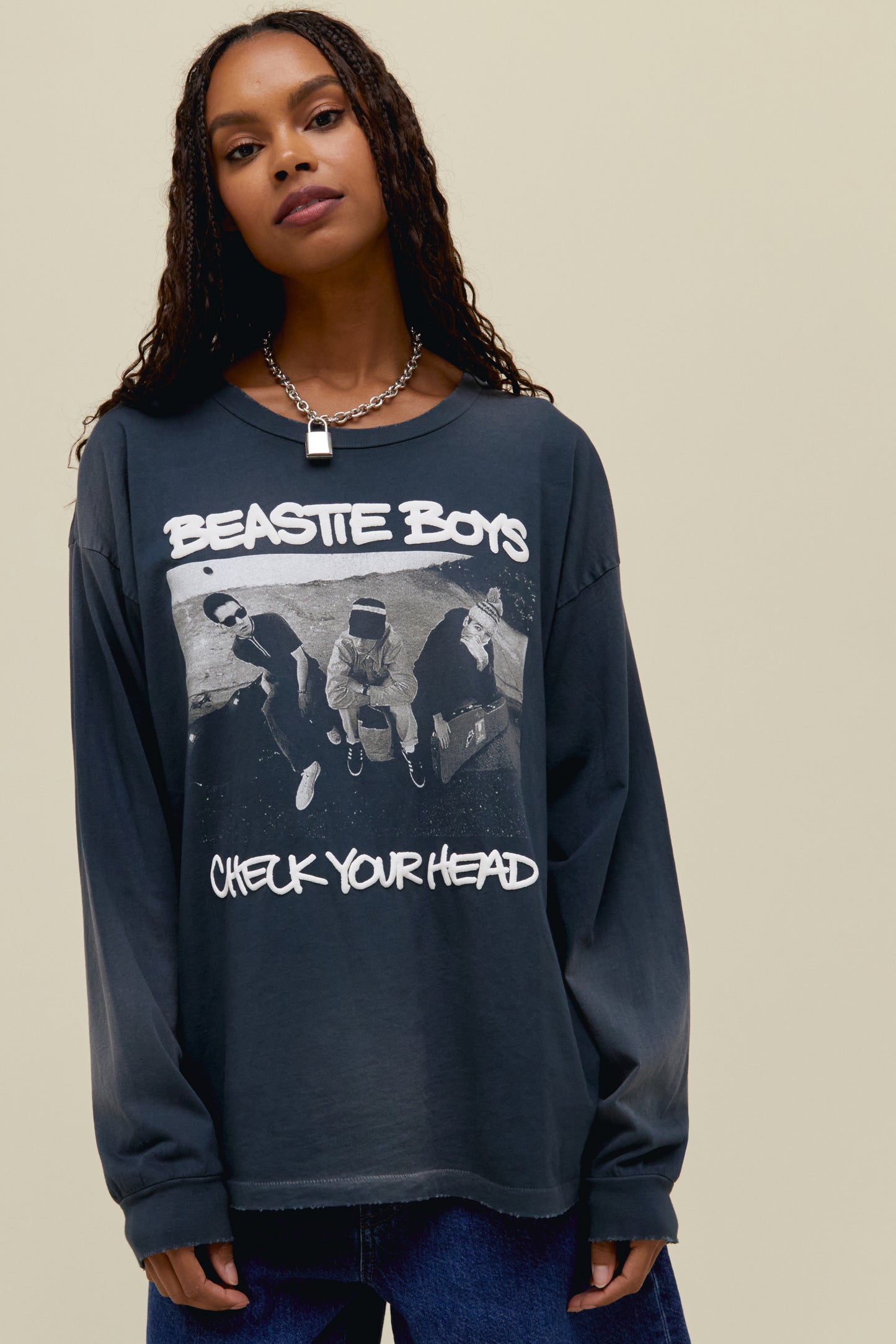 A dark-haired model featuring a black long sleeve stamped with 'Beastie Boys Check Your Head' and designed with the album's original art.