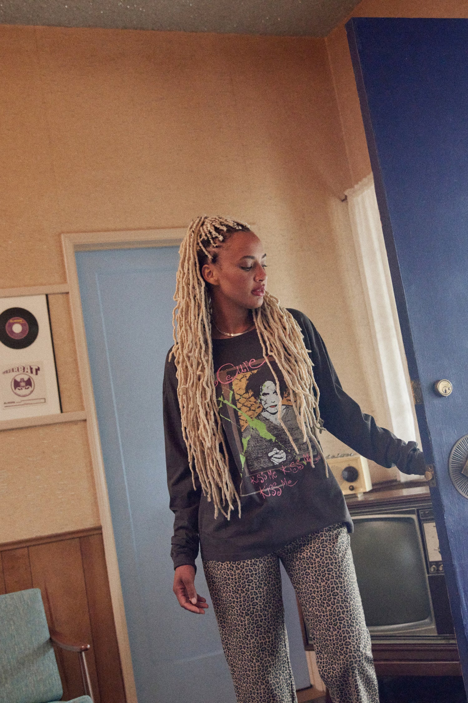 A model featuring a black The Cure long sleeve merch designed with a hand-drawn portrait of Smith and doodles in puff ink and pops of color.