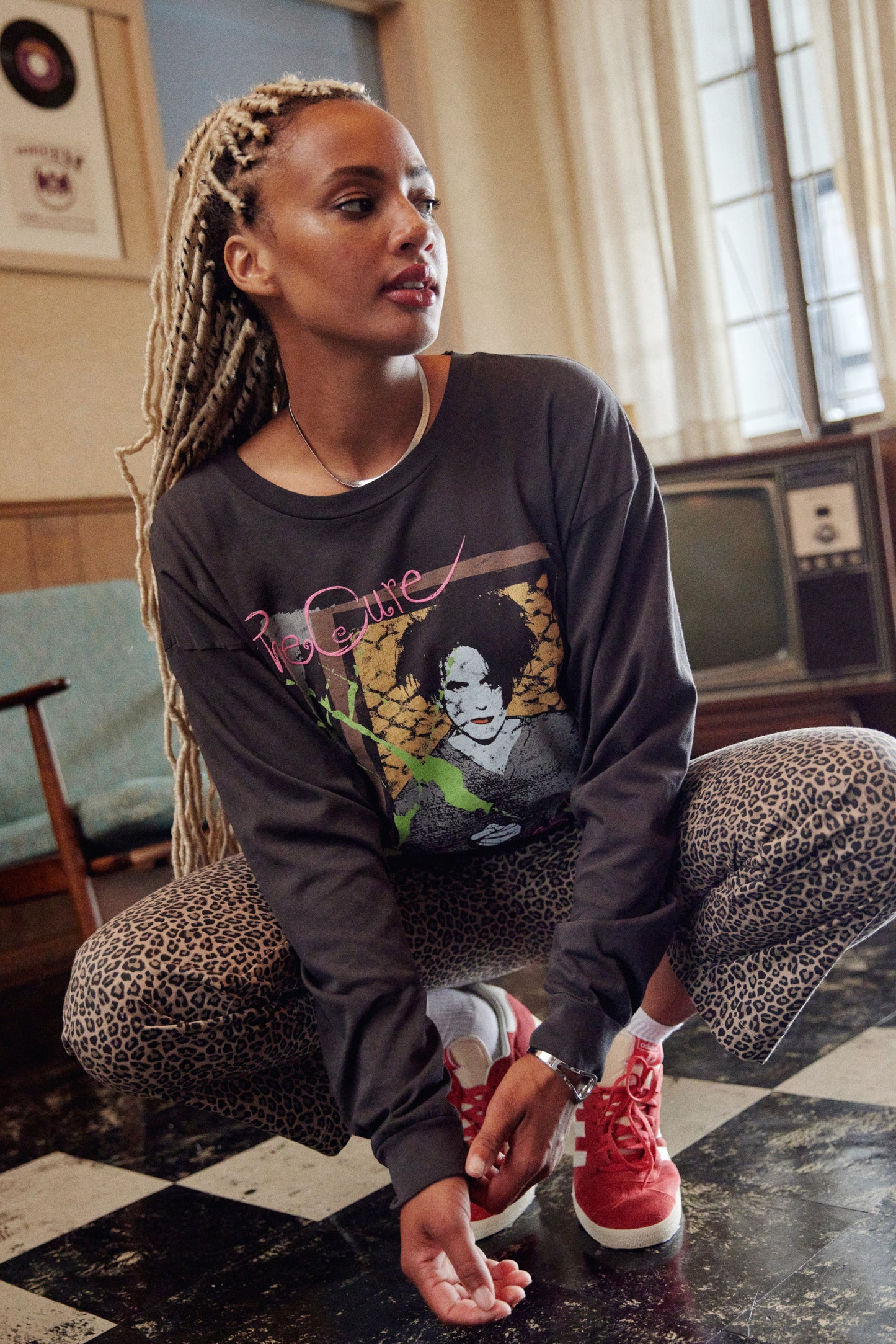 A model featuring a black The Cure long sleeve merch designed with a hand-drawn portrait of Smith and doodles in puff ink and pops of color.